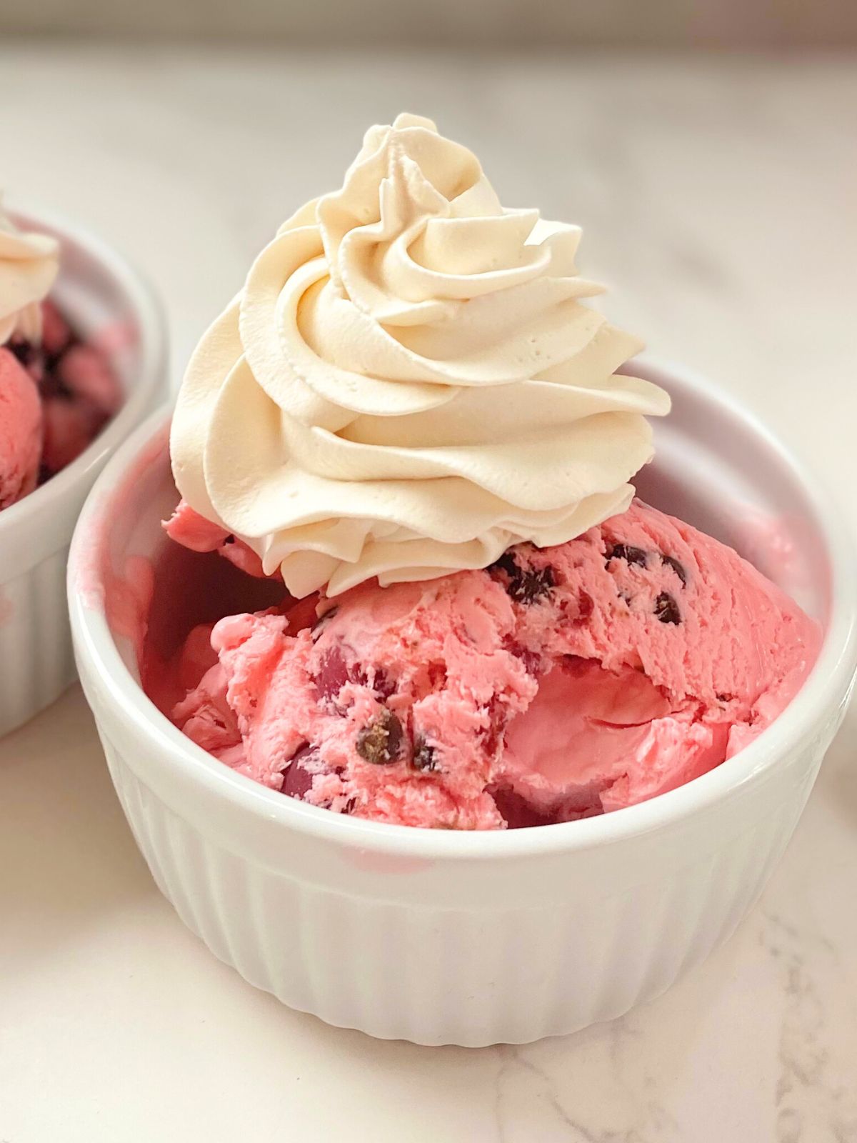 cherry chocolate ice cream in a bowl with whipped cream