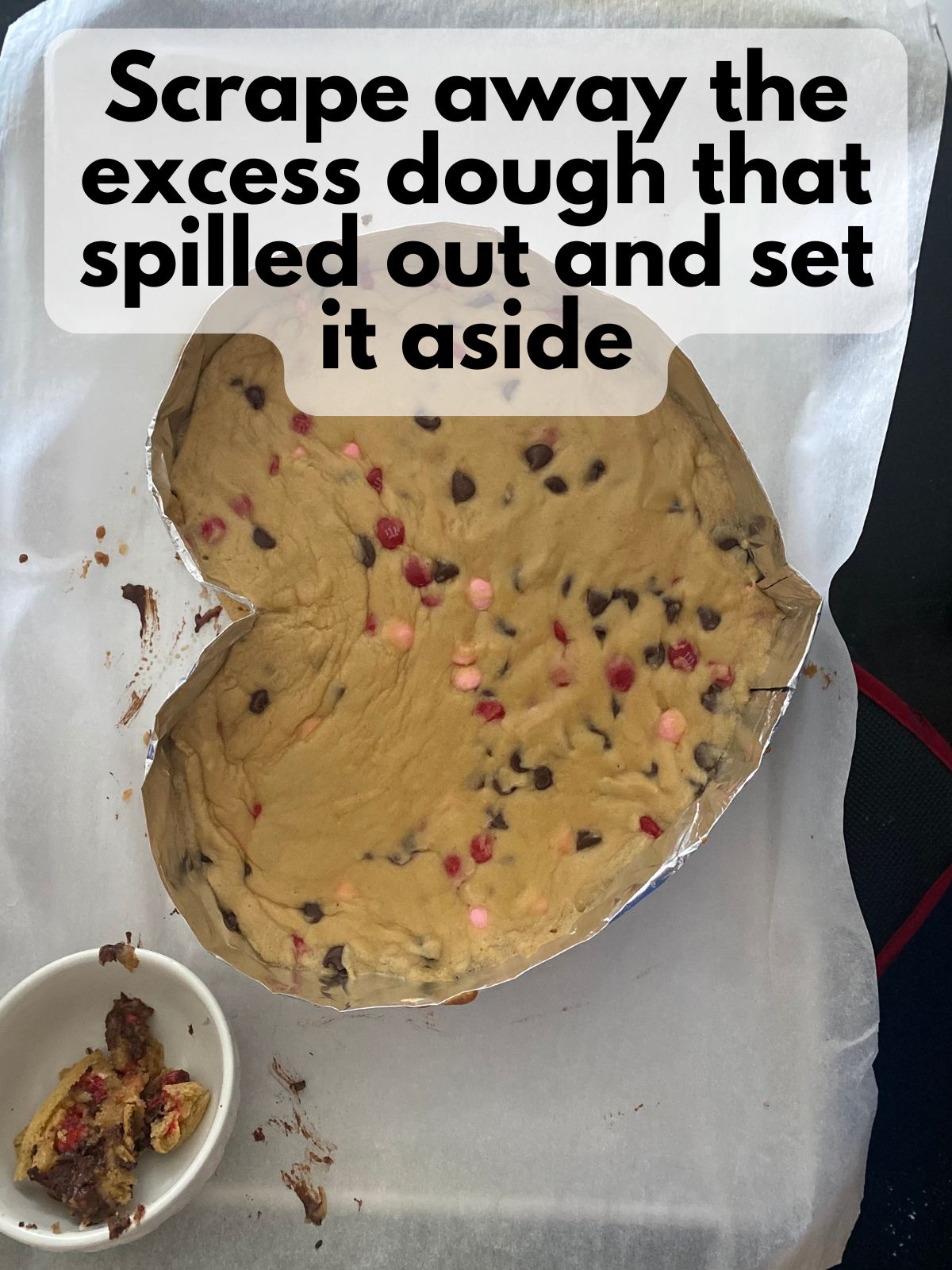 excess cookie dough that was scraped off of a heart cookie cake sitting separate in a bowl