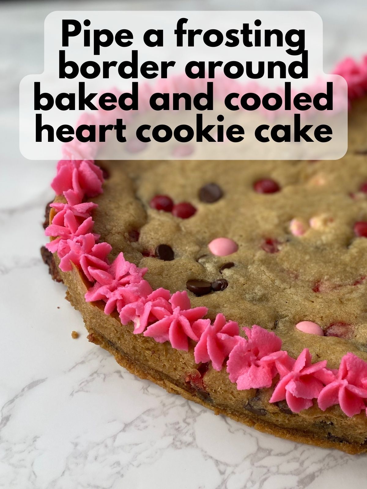 heart cookie cake with pink buttercream frosting piped around the eidges
