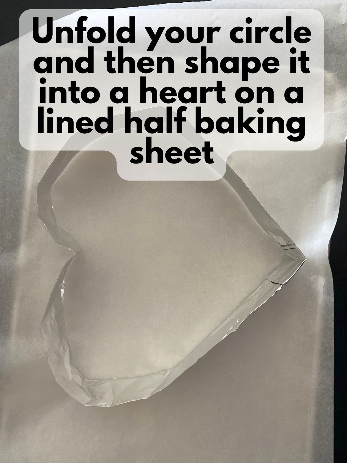 a heart-shaped mold made out of aluminum foil on a lined baking sheet