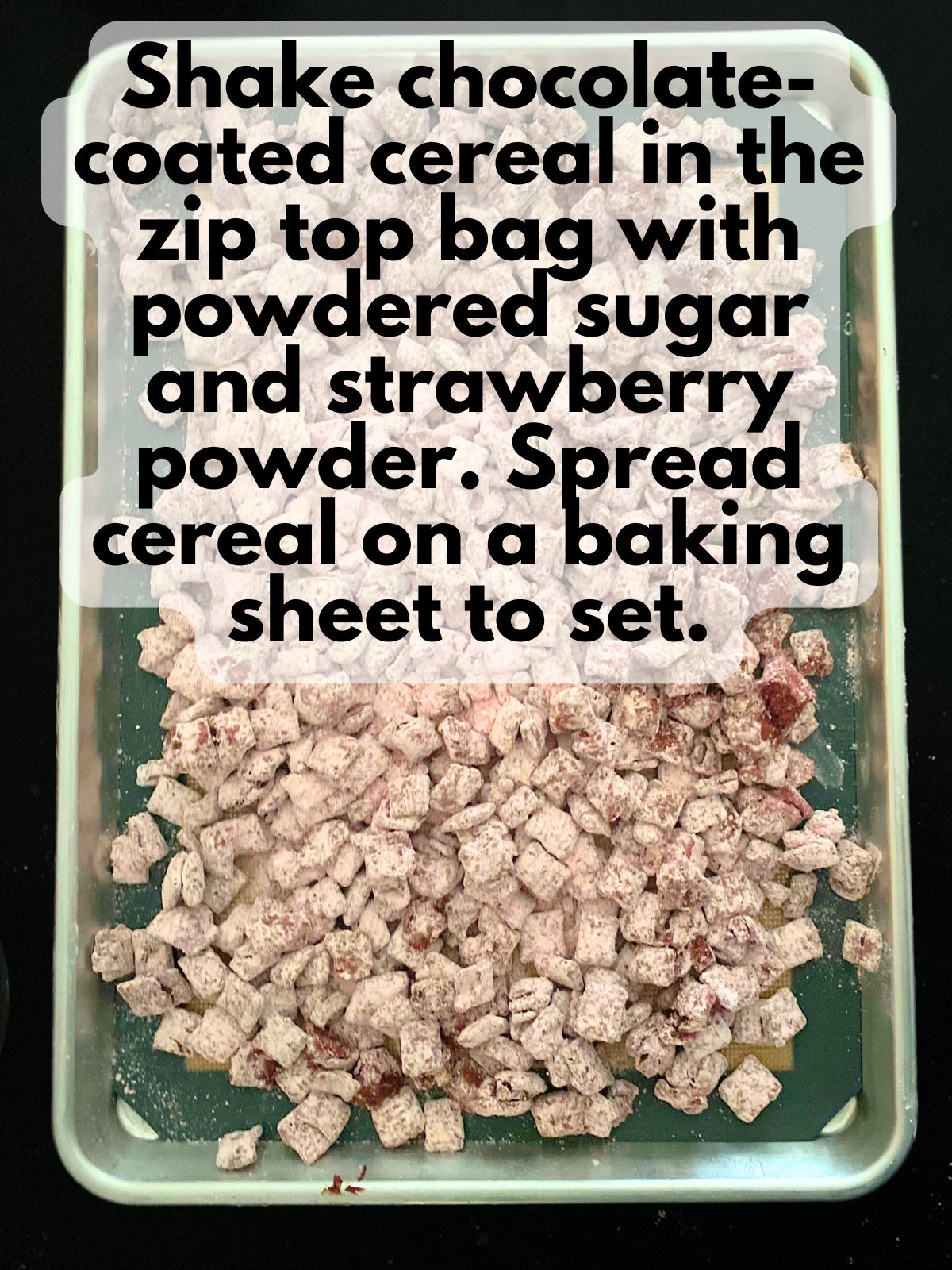 cereal coated in melted chocolate, powdered sugar and crushed freeze dried strawberries spread out on a baking sheet