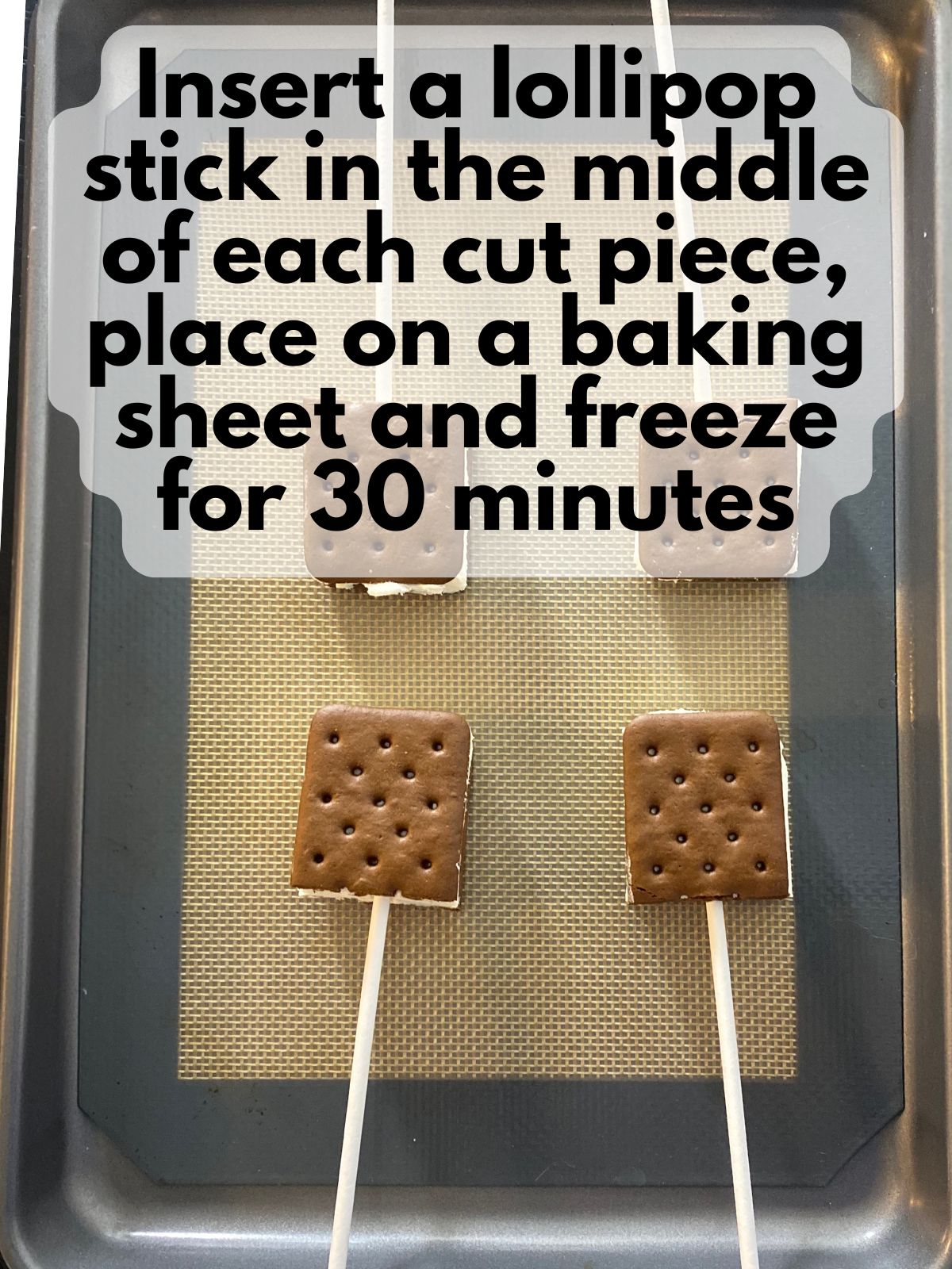 ice cream sandwiches but in half, with lollipop sticks inserted on a baking tray