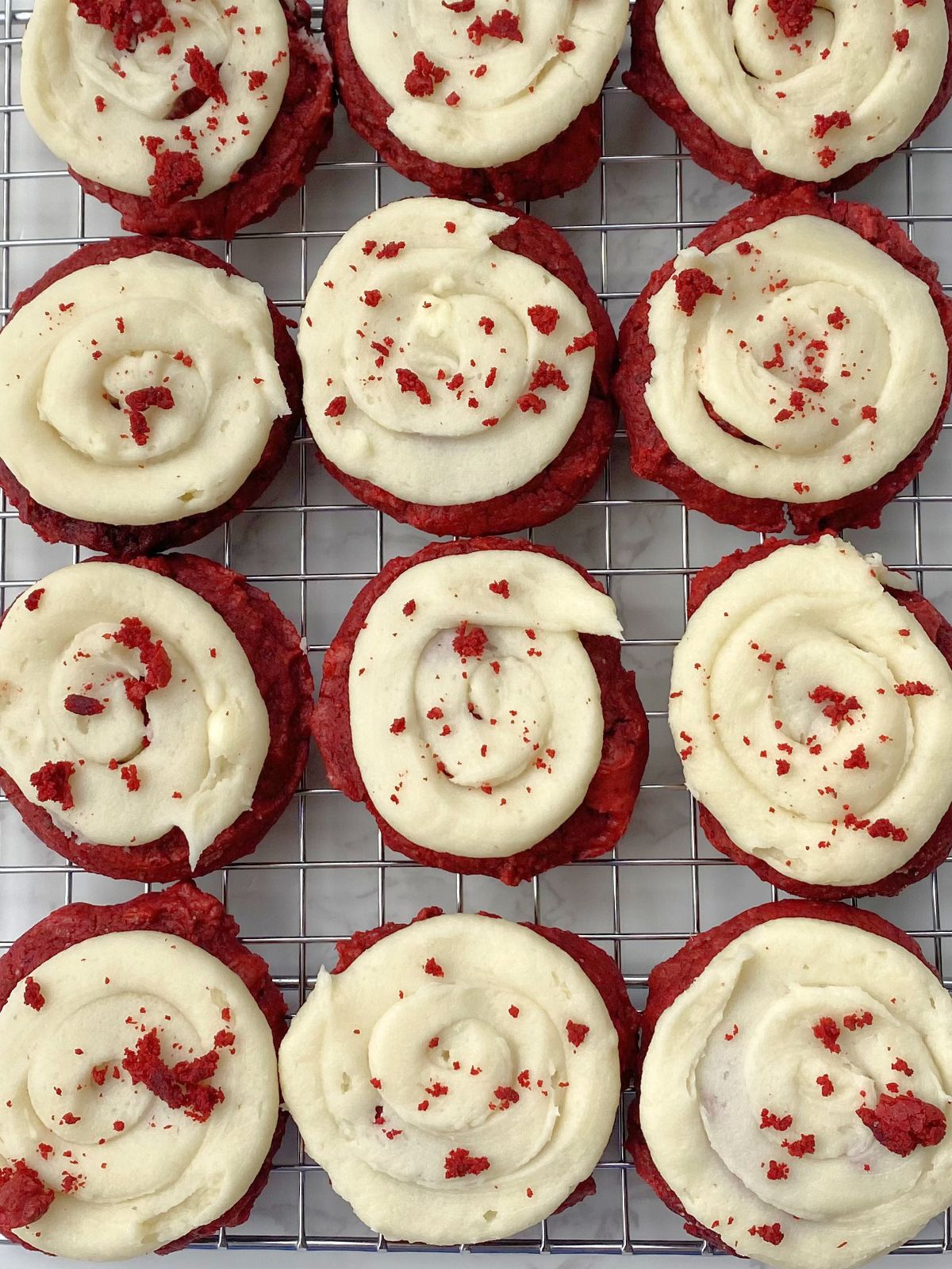 frosted red velvet cake mix cookies on a cooling rack