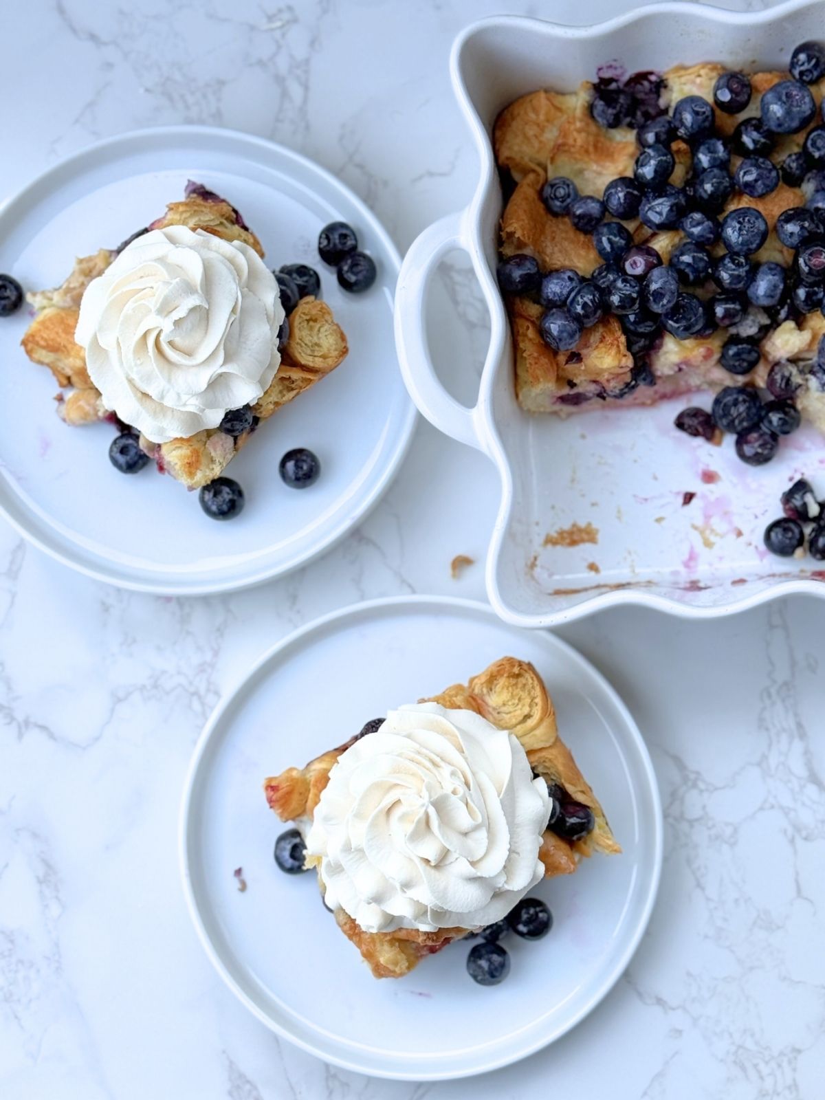 two slices of blueberry croissant bake topped with whipped cream