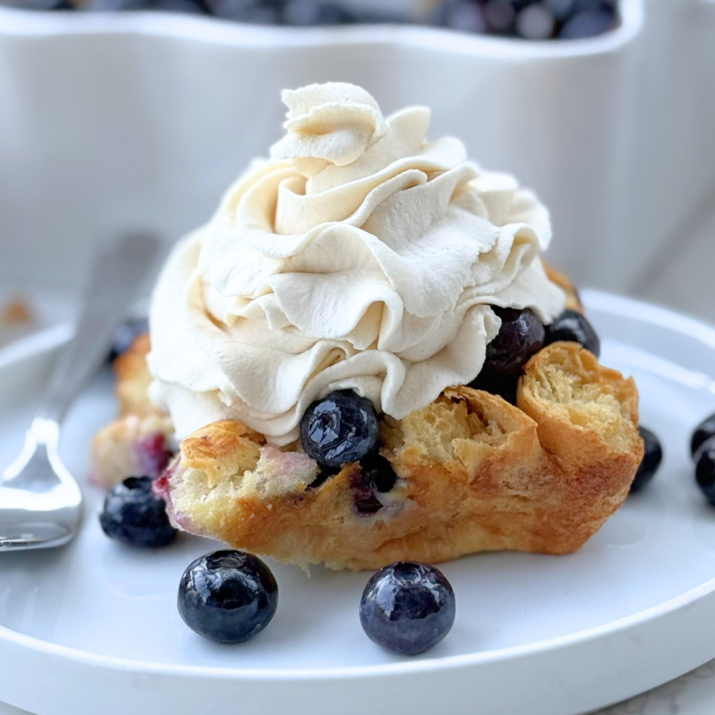 blueberry croissant bake on a plate with whipped cream