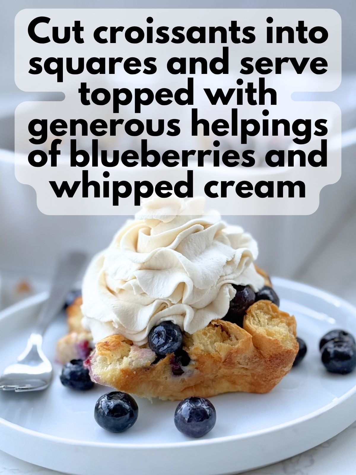 blueberry croissant bake cut into a square and topped with homemade whipped cream
