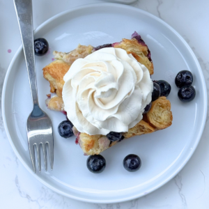 blueberry croissant bake with whipped cream on a plate