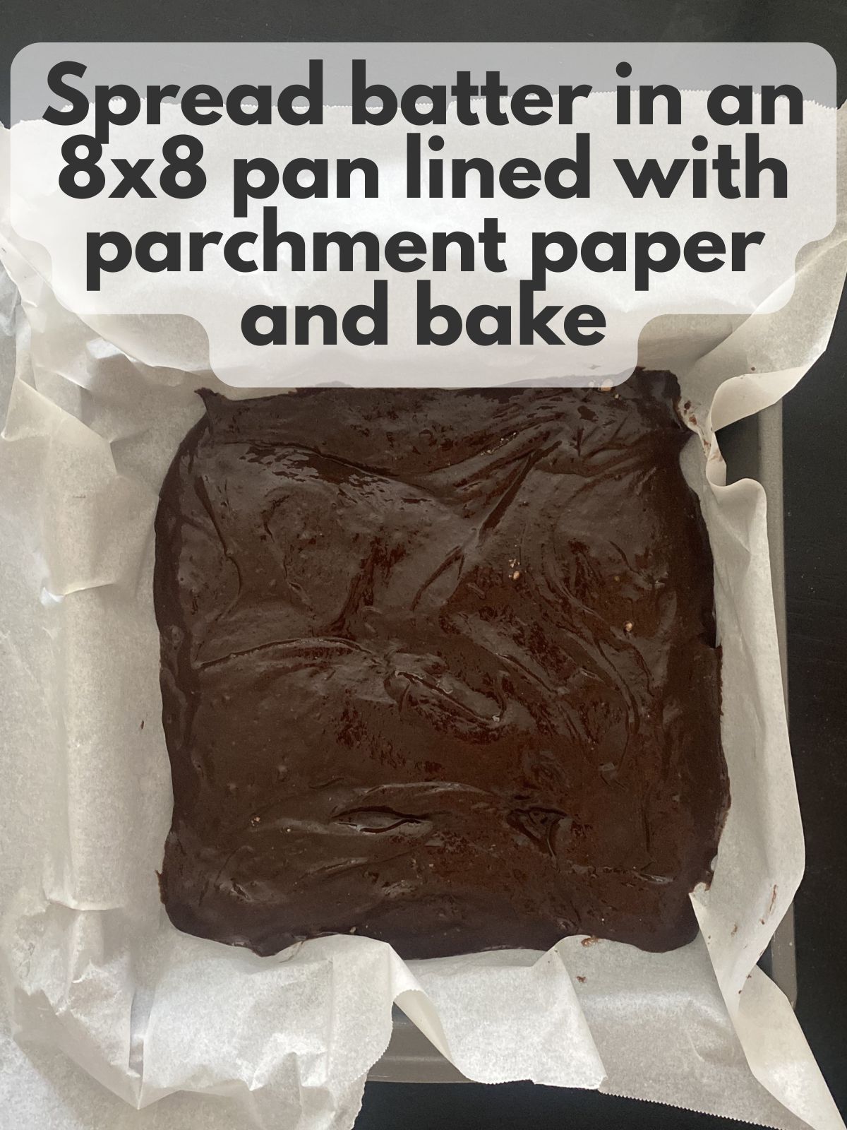 brownie batter in a square pan lined with parchment paper