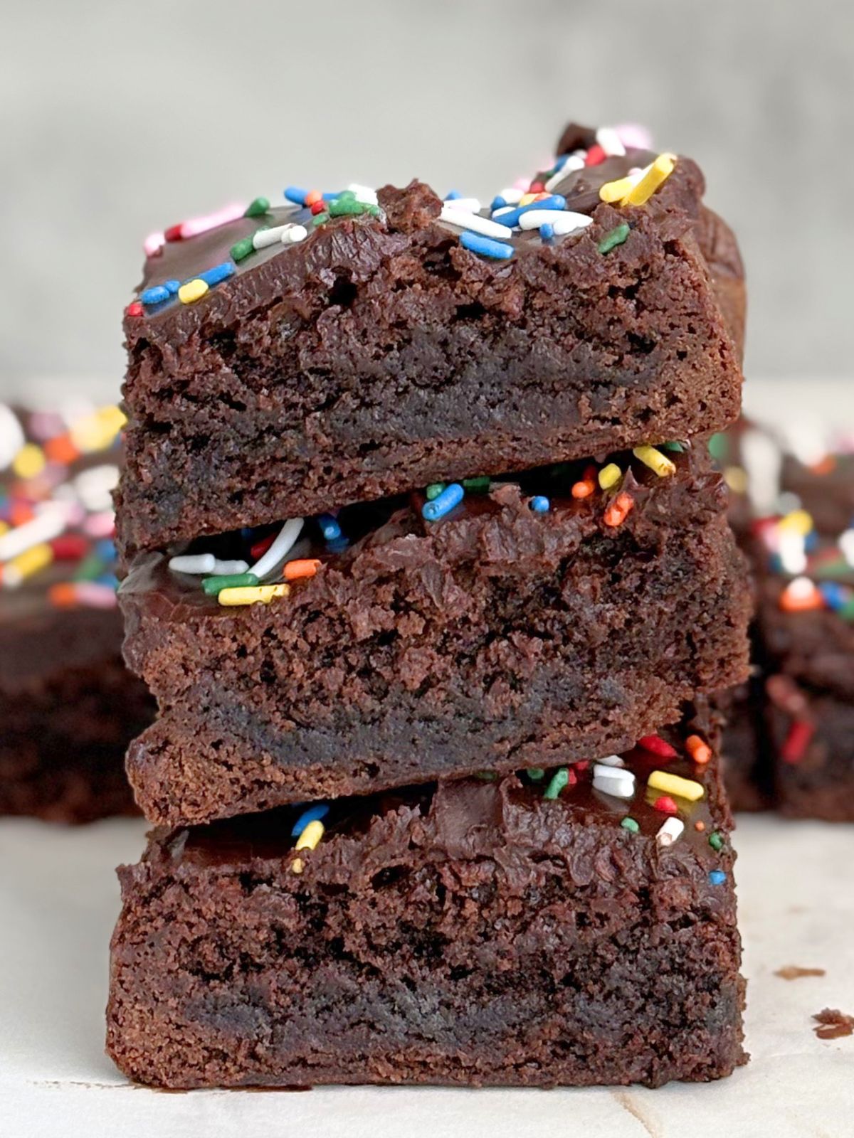 a stack of brownies with chocolate ganache and sprinkles