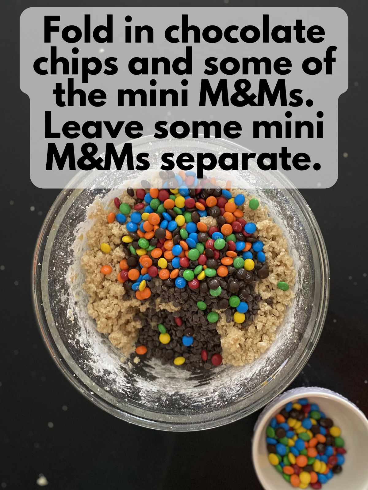 mini M&Ms and mini chocolate chips folded into cookie dough, some mini M&Ms in a bowl set to the side