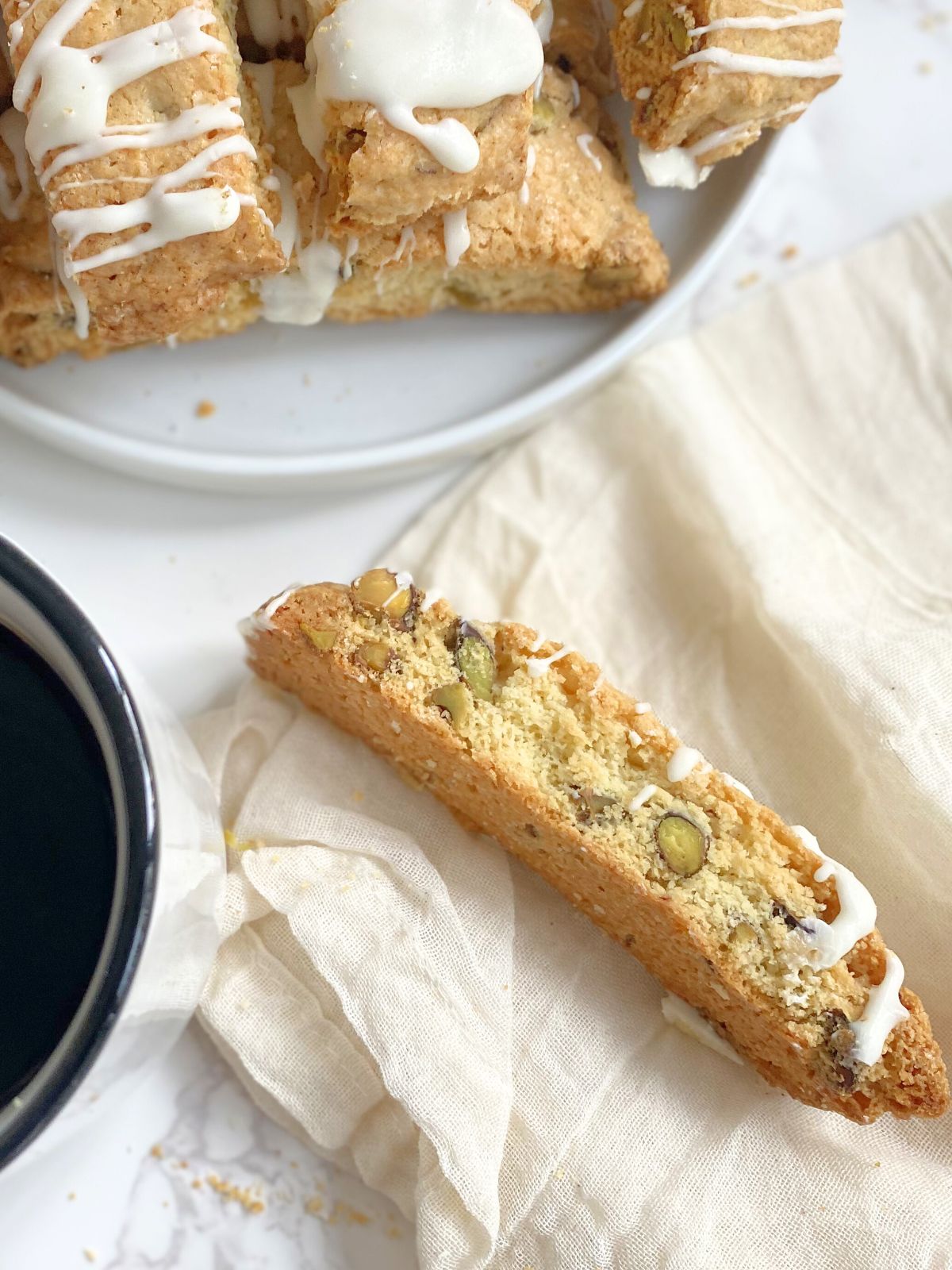 pistachio biscotti resting on a napkin next to a mug of coffee