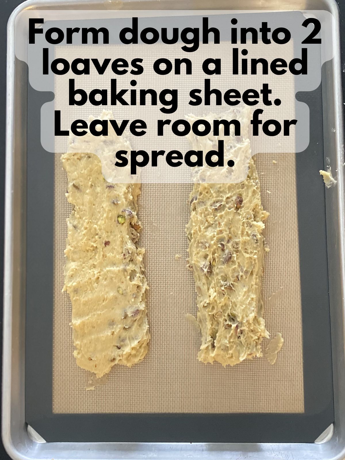 pistachio biscotti dough formed into two loaves on a lined baking sheet