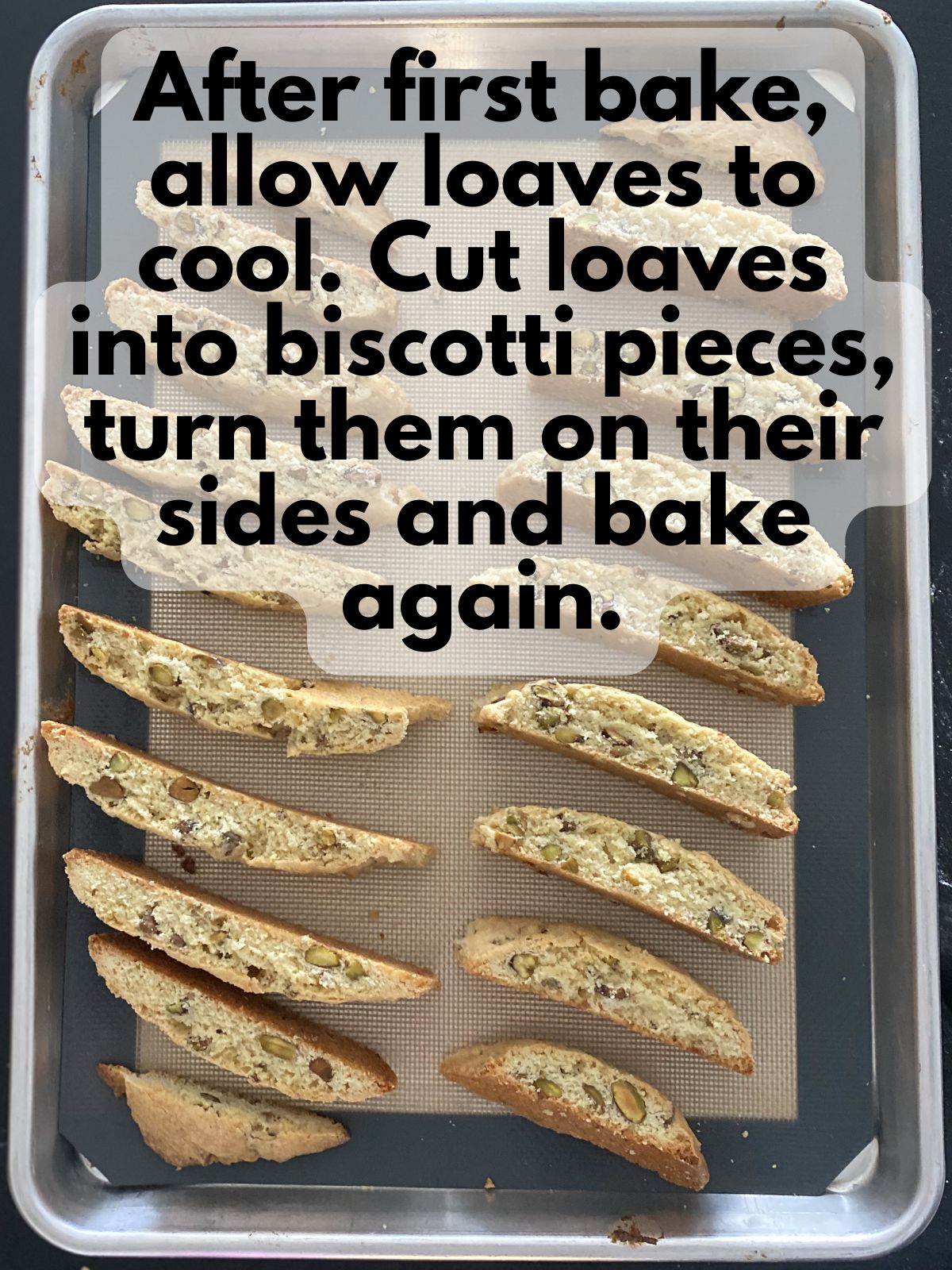 pistachio biscotti on a baking sheet, cut side down