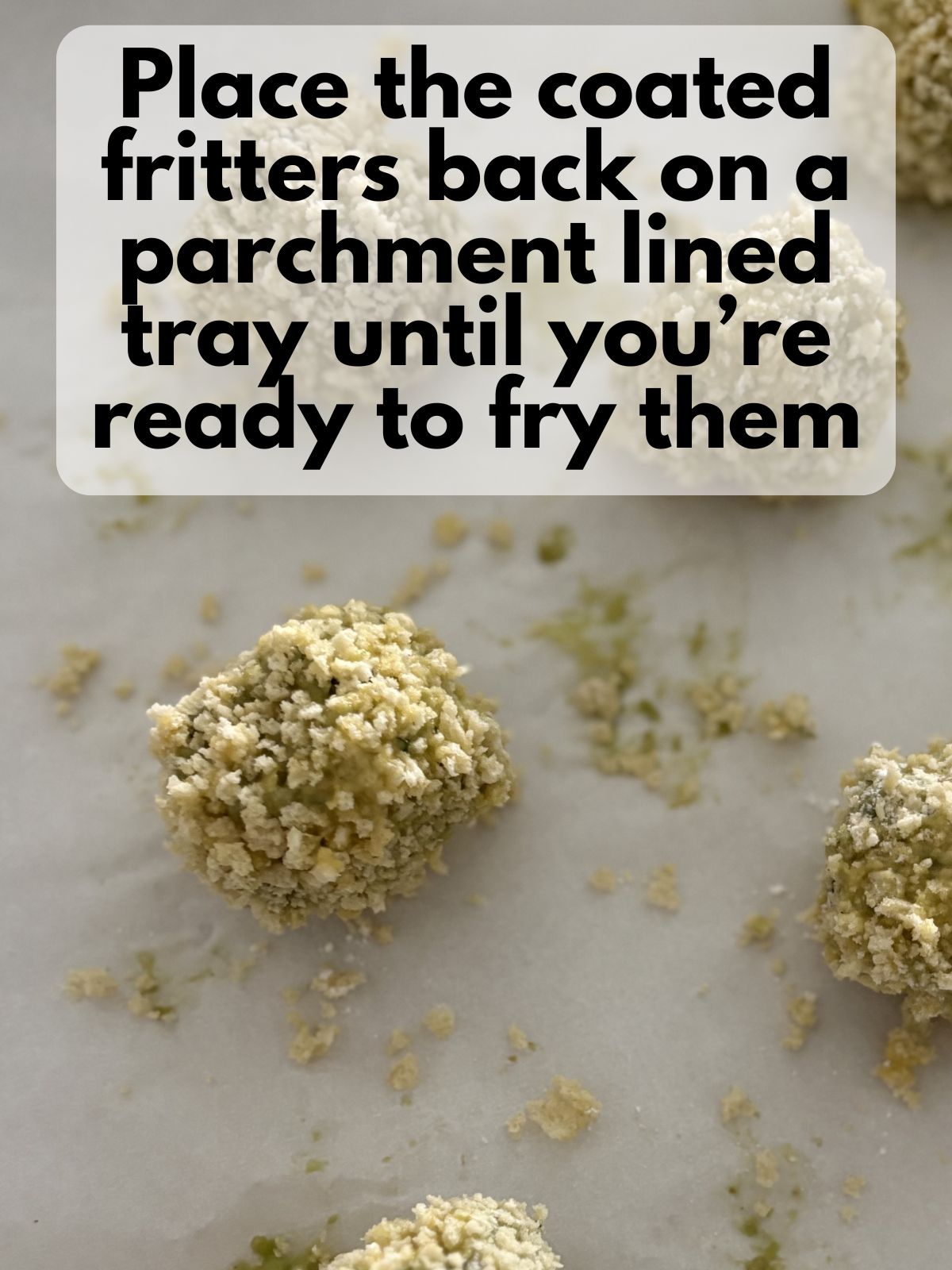 breaded avocado and cheese fritters sitting on a lined baking sheet