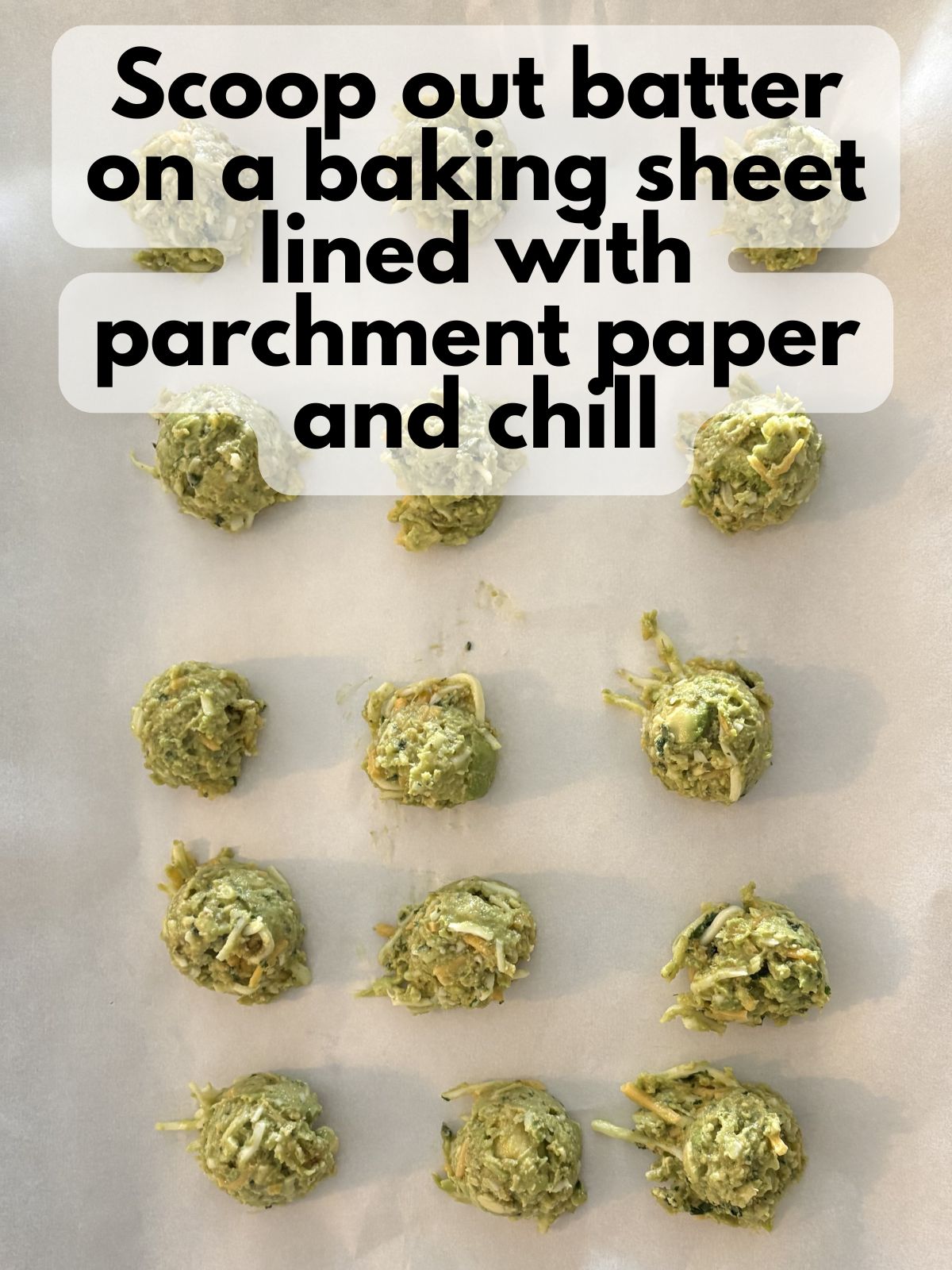 formed avocado and cheese fritters sitting on a baking sheet lined with parchment paper