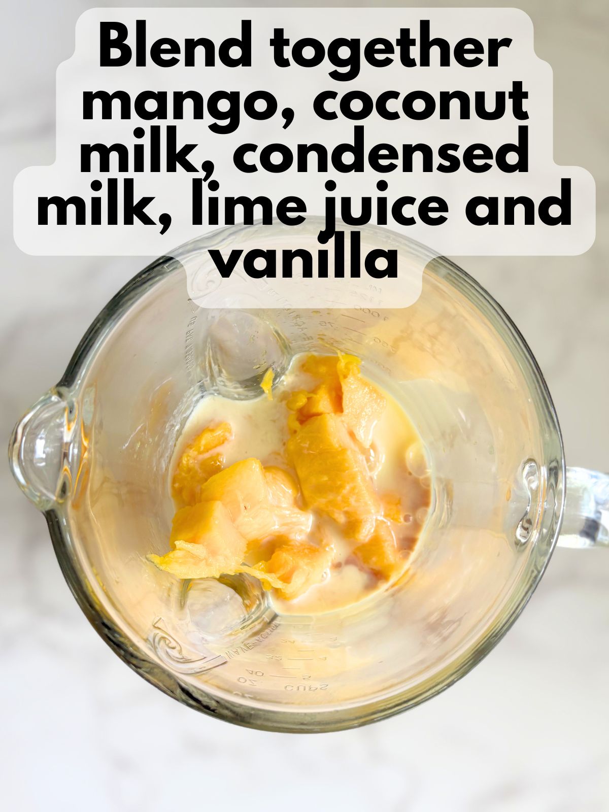 mango chunks in a blender with coconut milk, condensed milk, lime juice and vanilla