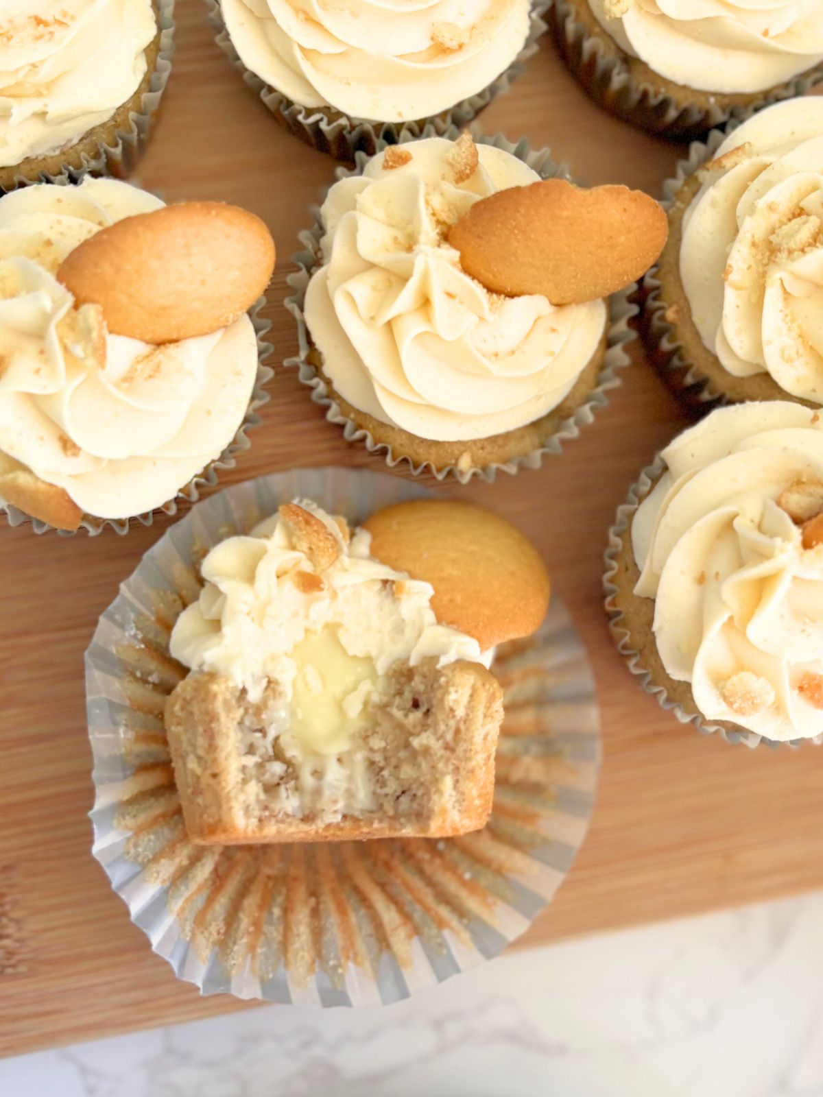 banana pudding cupcakes on a trap, a large bite is taken out of one displaying the pudding filling