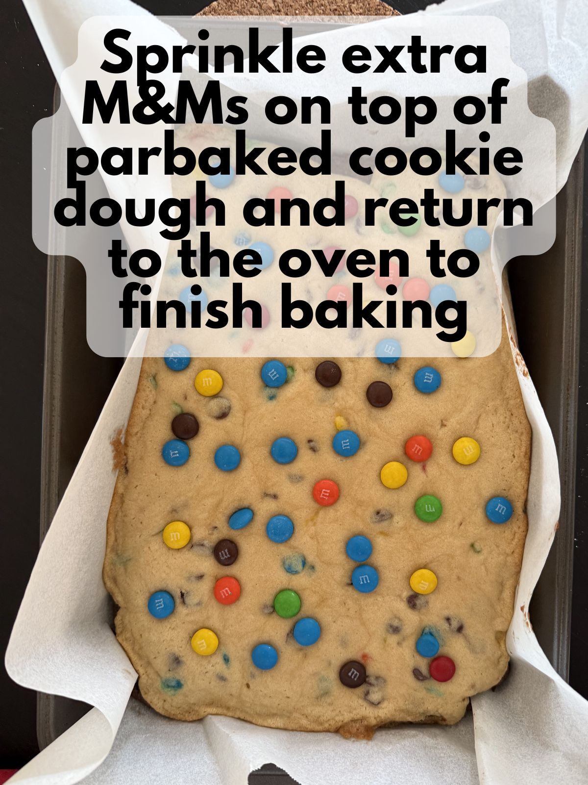 M&Ms sprinkled on top of parbaked cookie dough