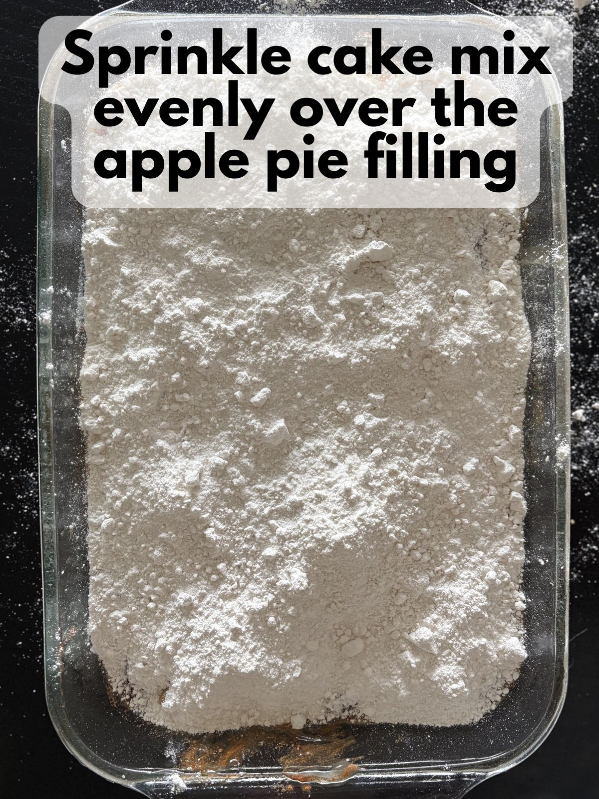 cake mix sprinkled over apple pie filling spread in a 9x13 dish