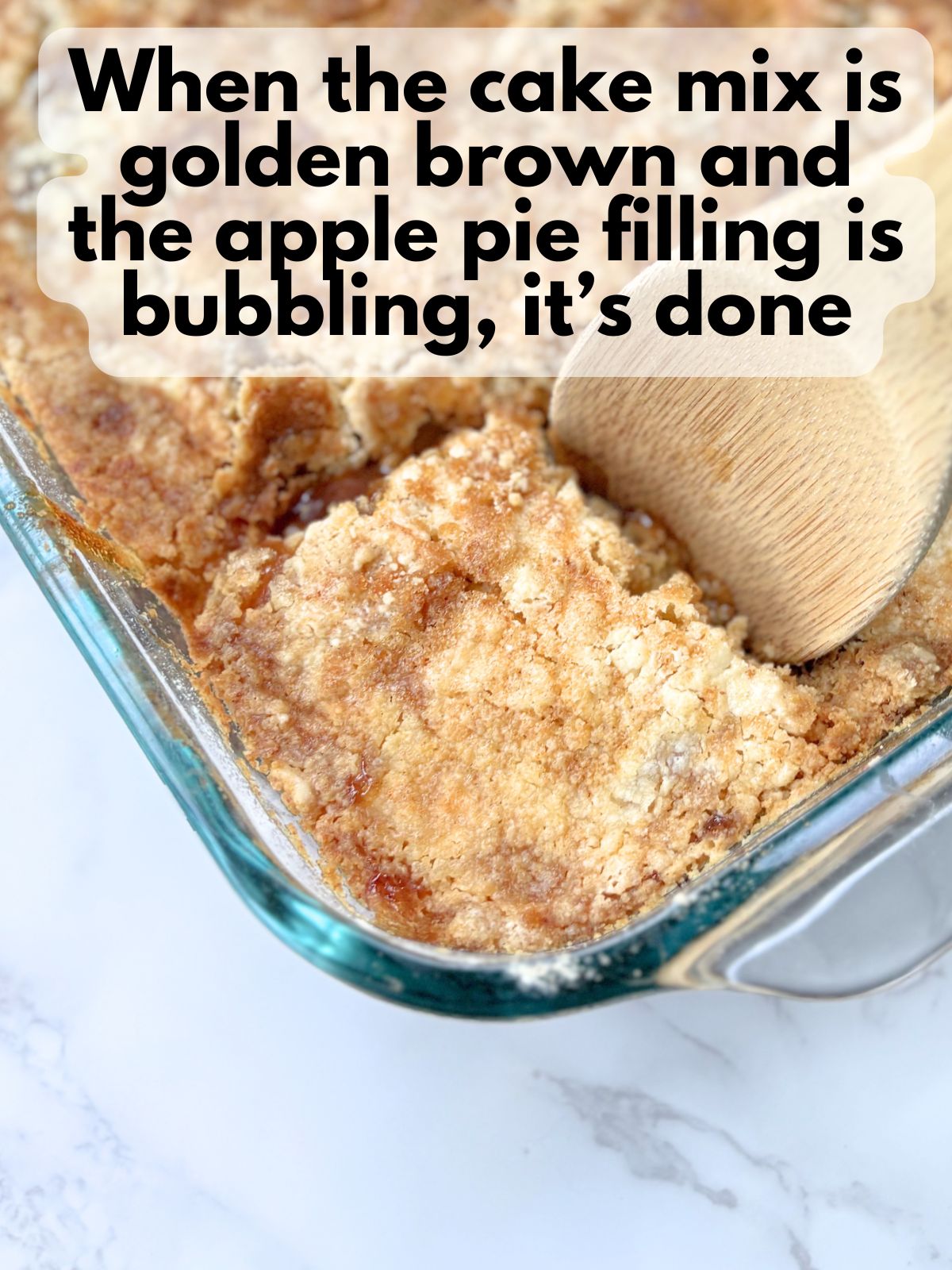 scooping a slice of finished apple cobbler with a golden top and bubbling apple pie filling
