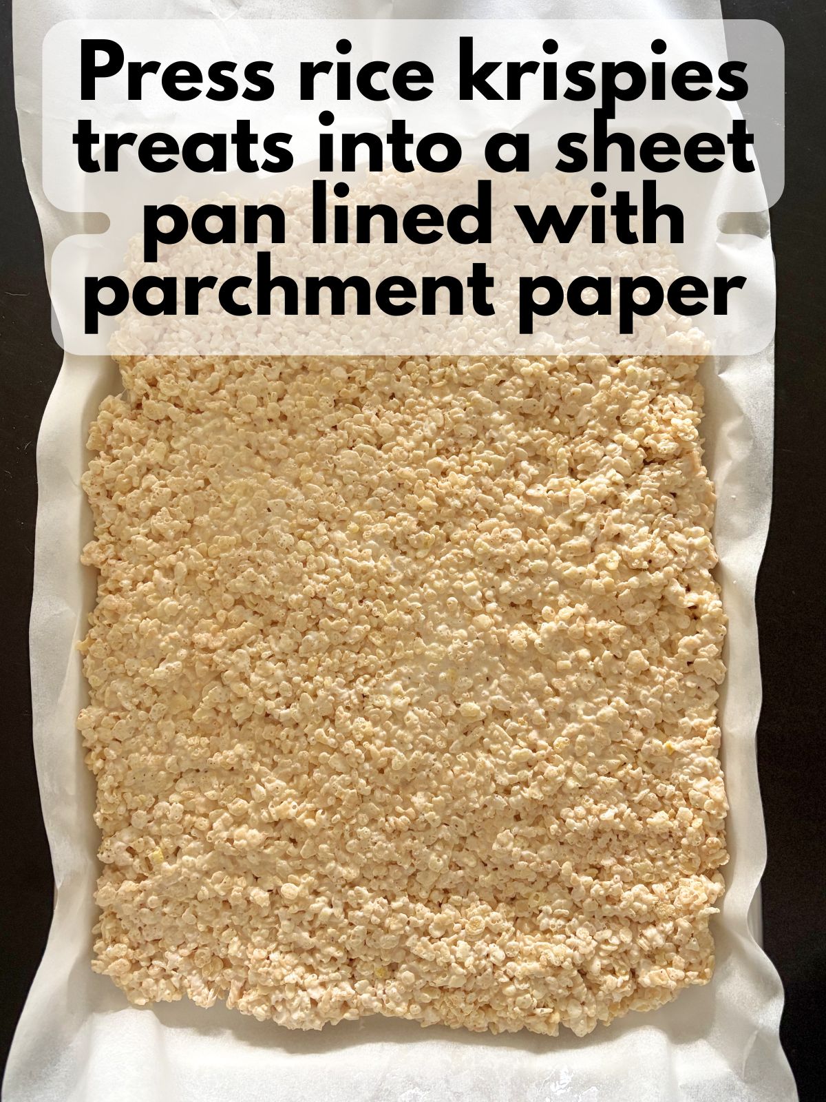 rice krispie treats pressed into a sheet pan lined with parchment paper