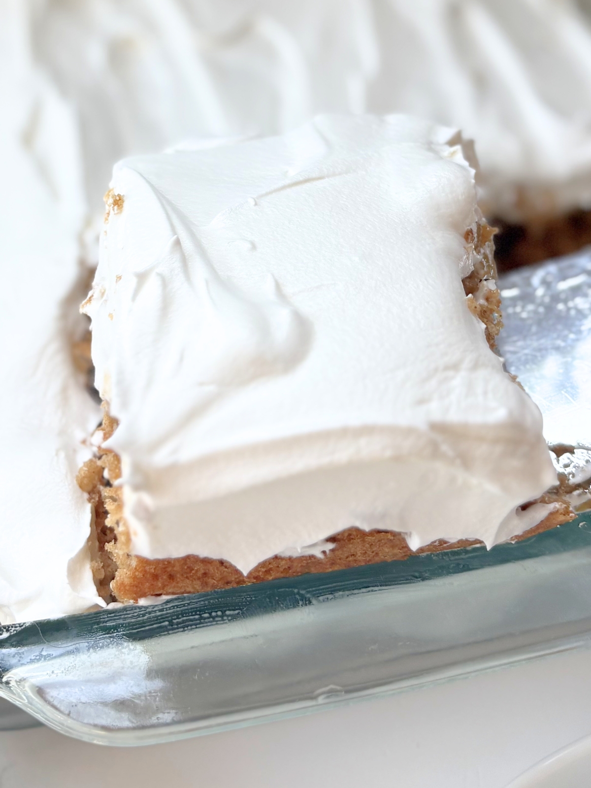 a slice of apple caramel poke cake being taken out of the pan