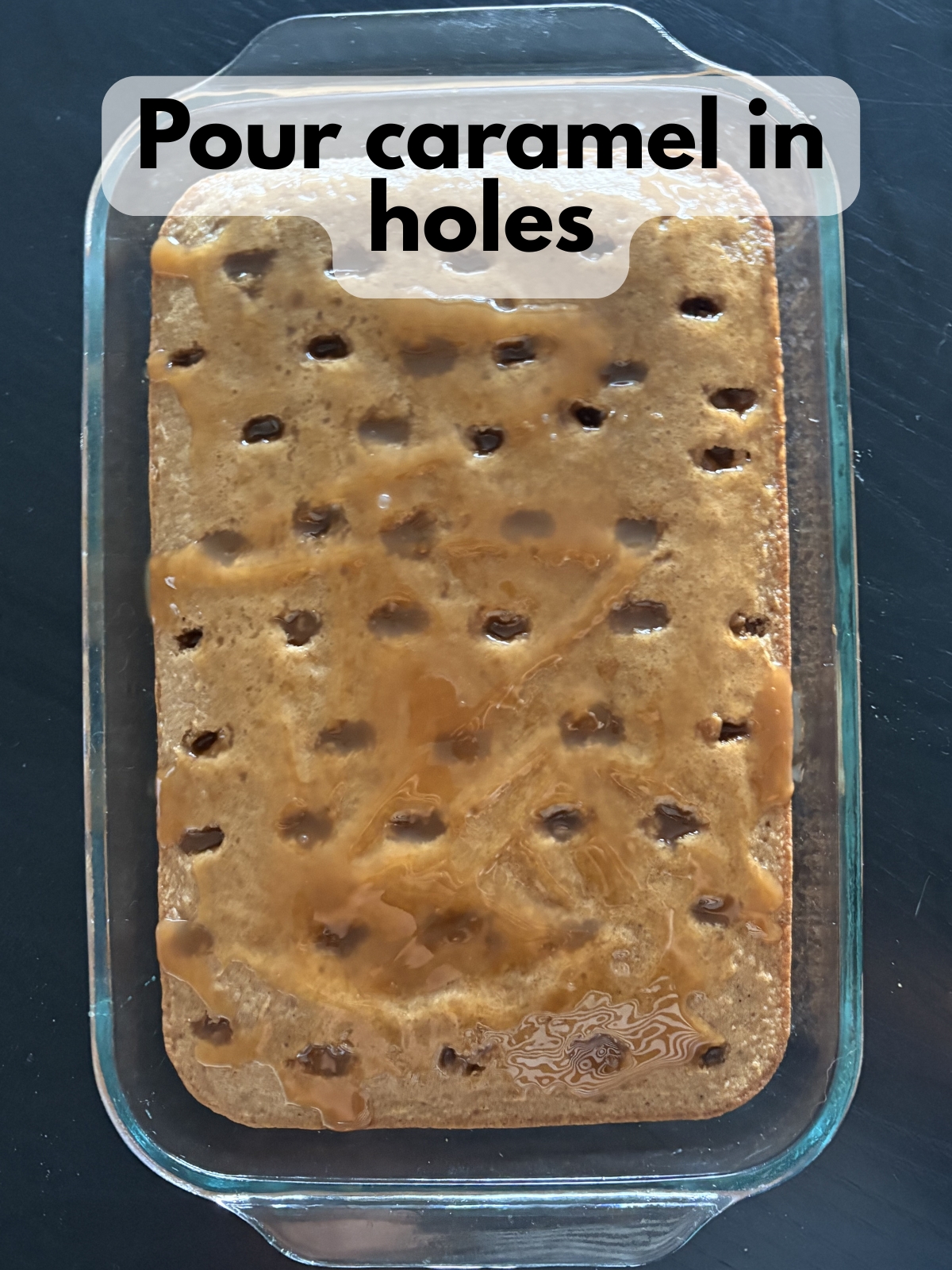 caramel filling spread over cake poked with holes
