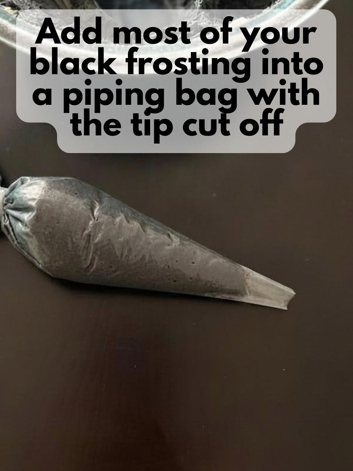 black frosting in a piping bag with the end snipped off