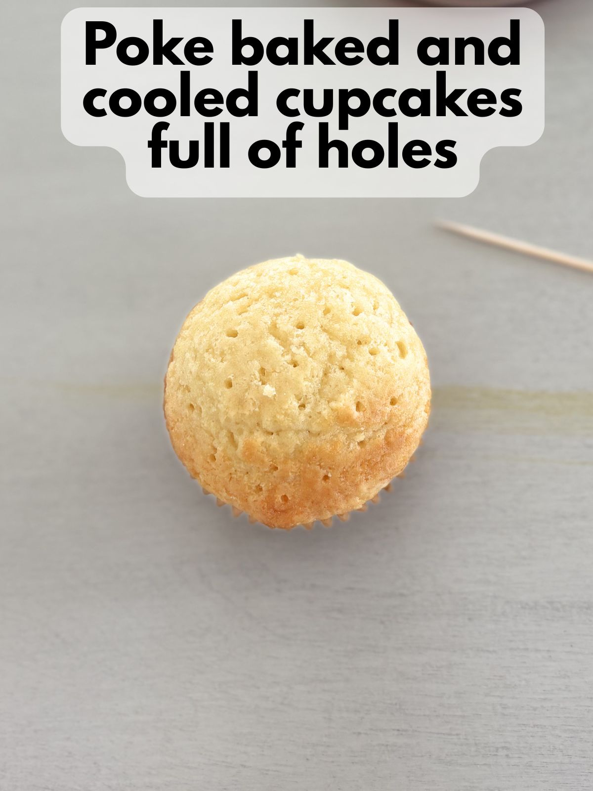 a baked gluten free yellow cupcake with many small holes from being poked with a toothpick