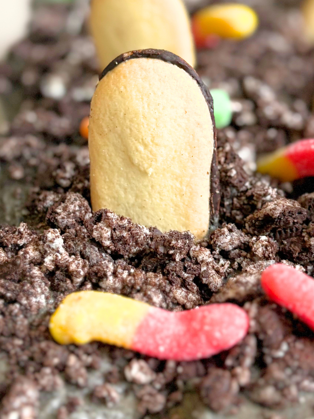 close up of a cookie tombstone on graveyard cupcake cake