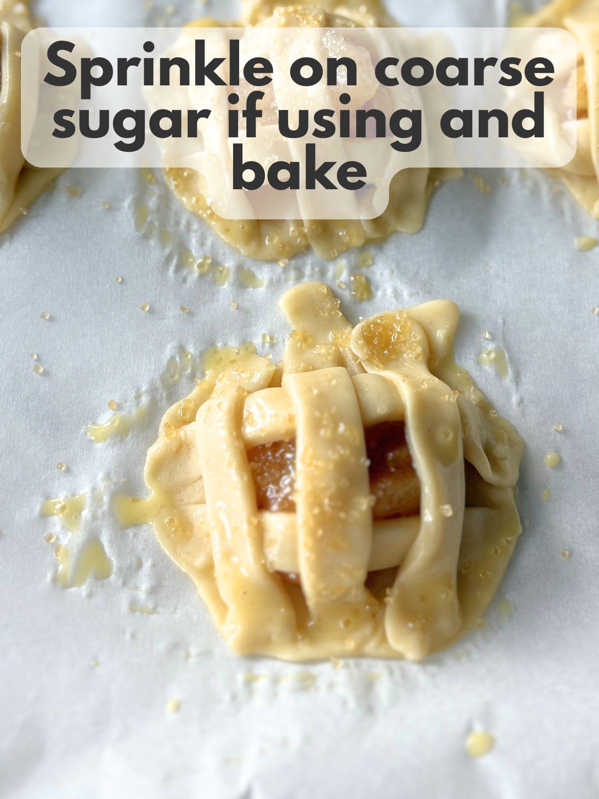 coarse sugar sprinkled over mini apple pies with egg wash