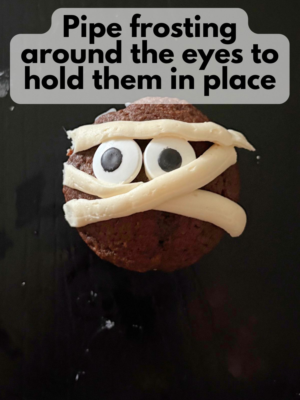 chocolate cupcake with candy eyes held in plac with vanilla buttercream frosting