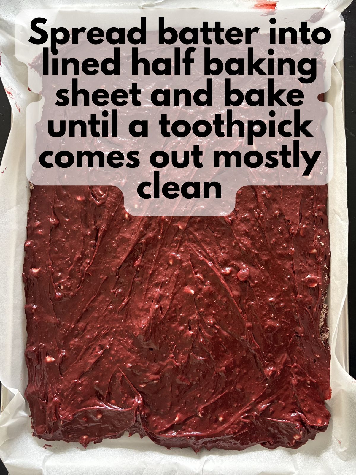 red velvet brownie batter spread in a half baking sheet