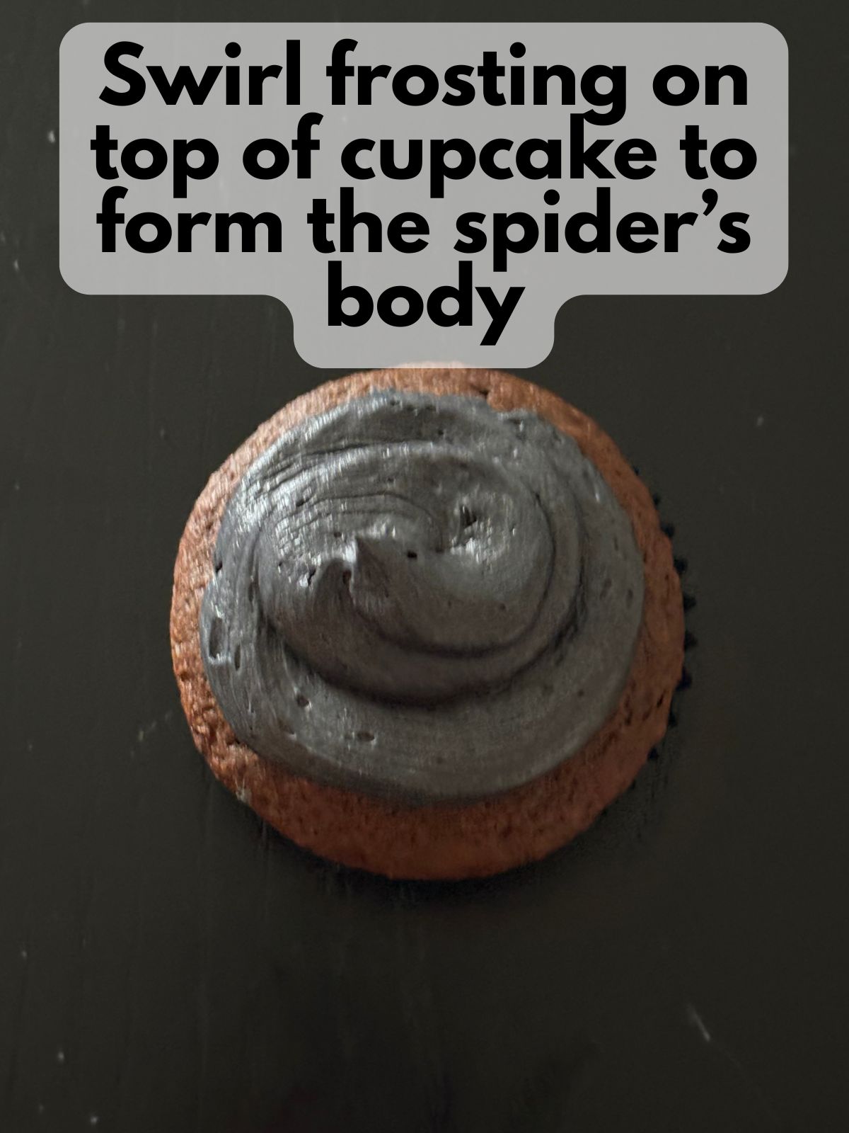 black frosting piped onto a chocolate cupcake to look like a spider body