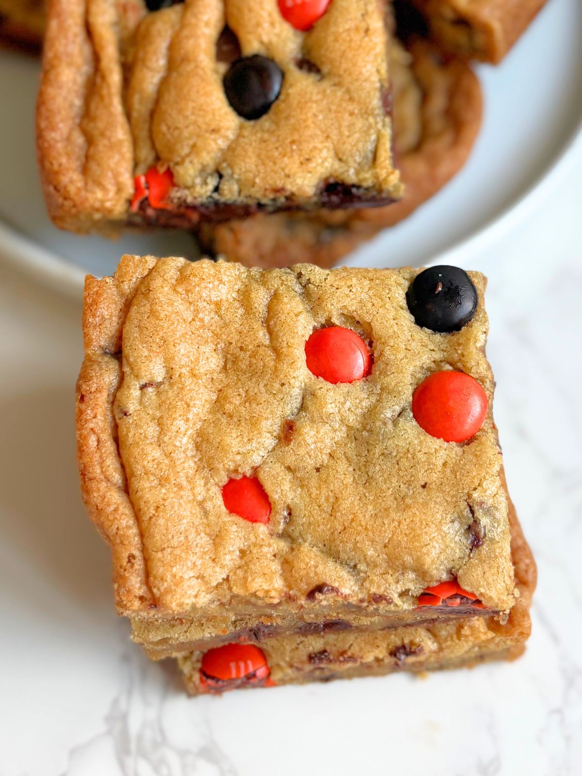 Halloween M&M cookie bars on a plate and in a stack next to the plate