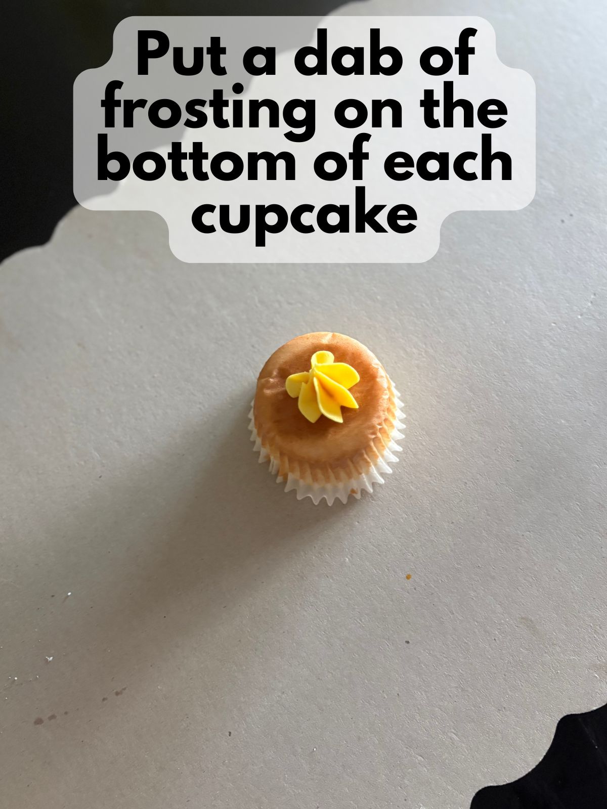 a dab of frosting on the bottom of a cupcake
