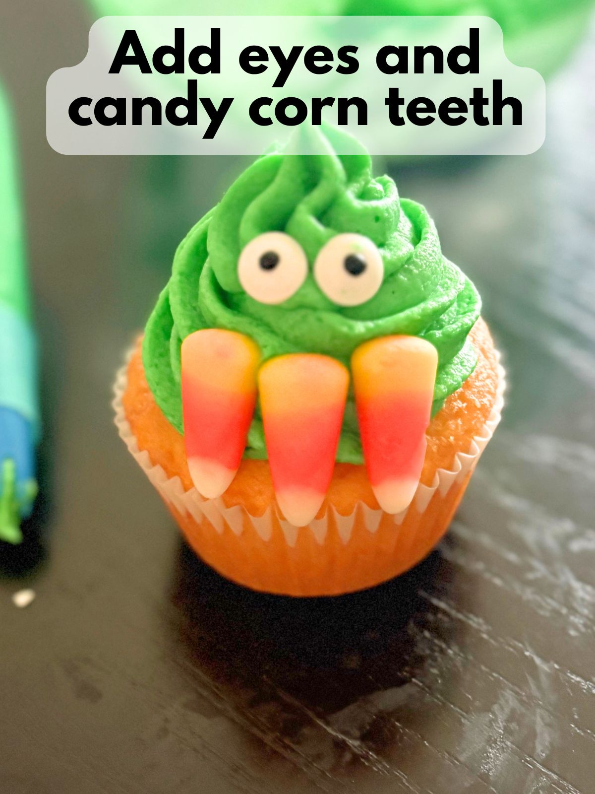 eyes and candy corn teeth pressed into frosting to make a monster face