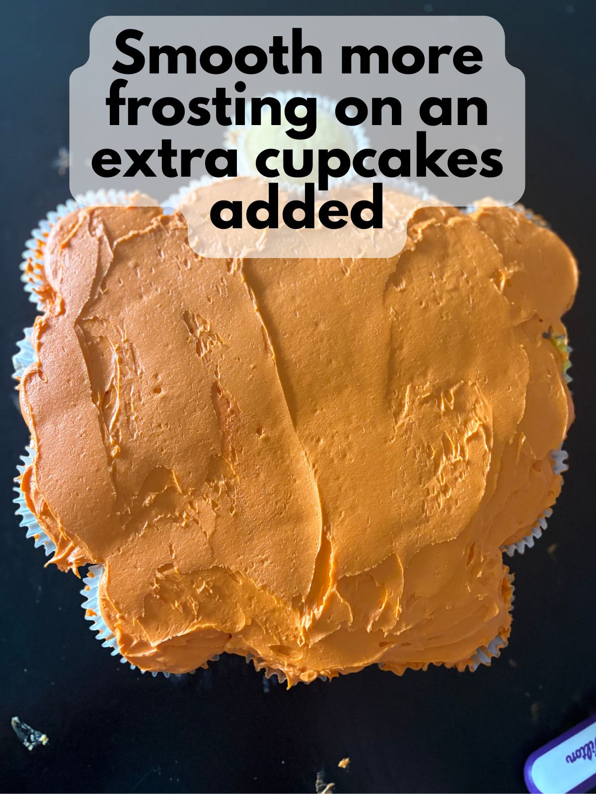 orange frosting spread over the top of a pumpkin-shaped cupcake cake