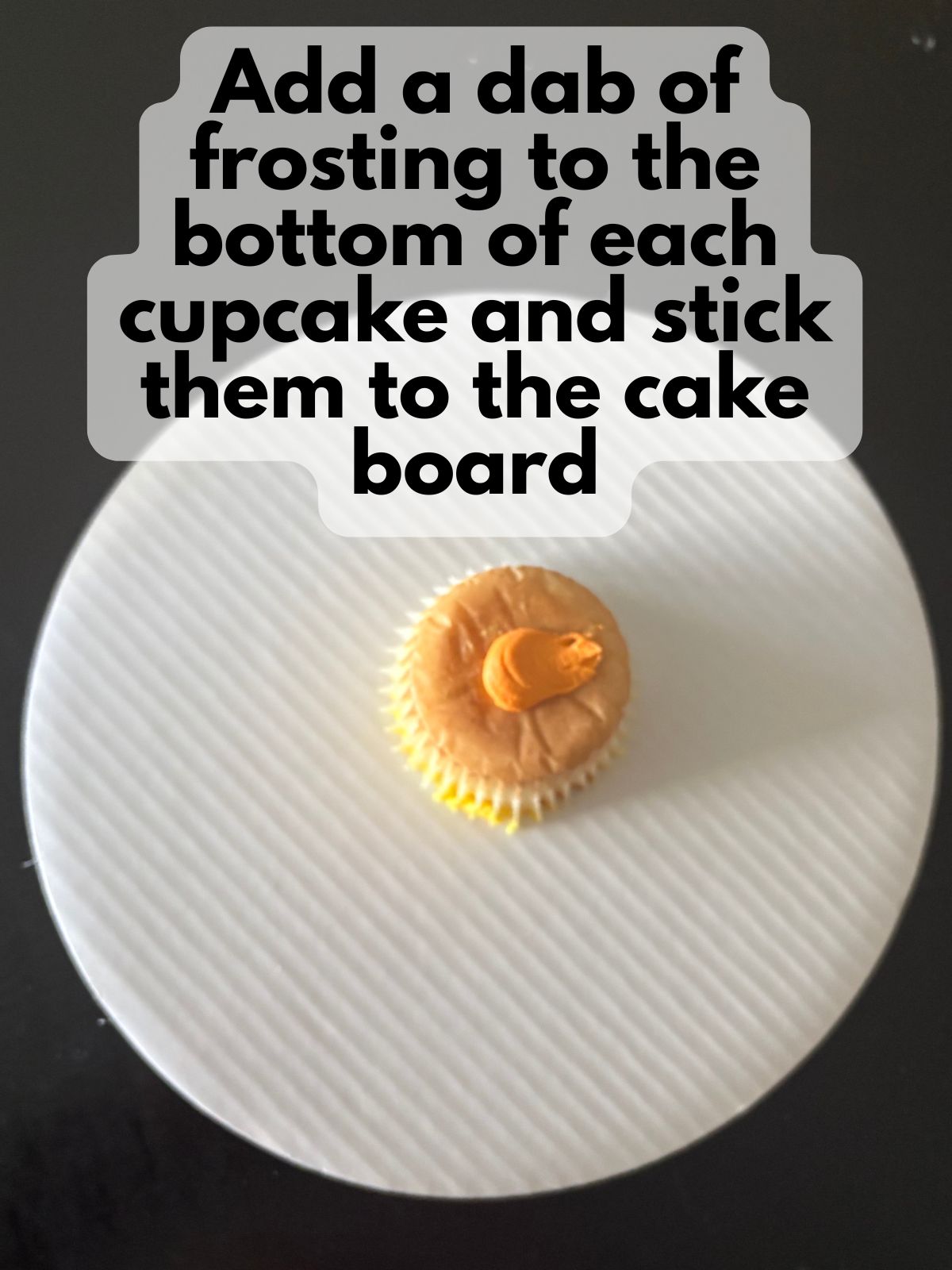 a dab of frosting on the bottom of a cupcake on top of a cake board