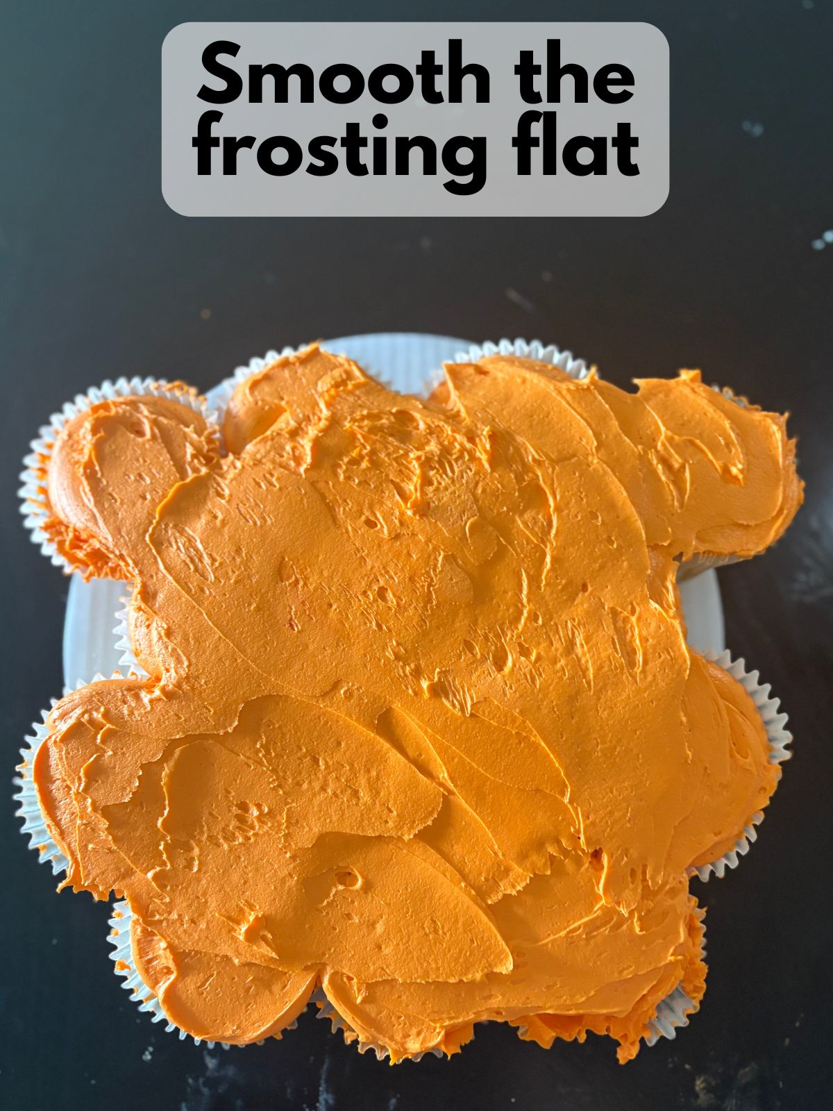 orange frosting spread over the top of a cupcake cake