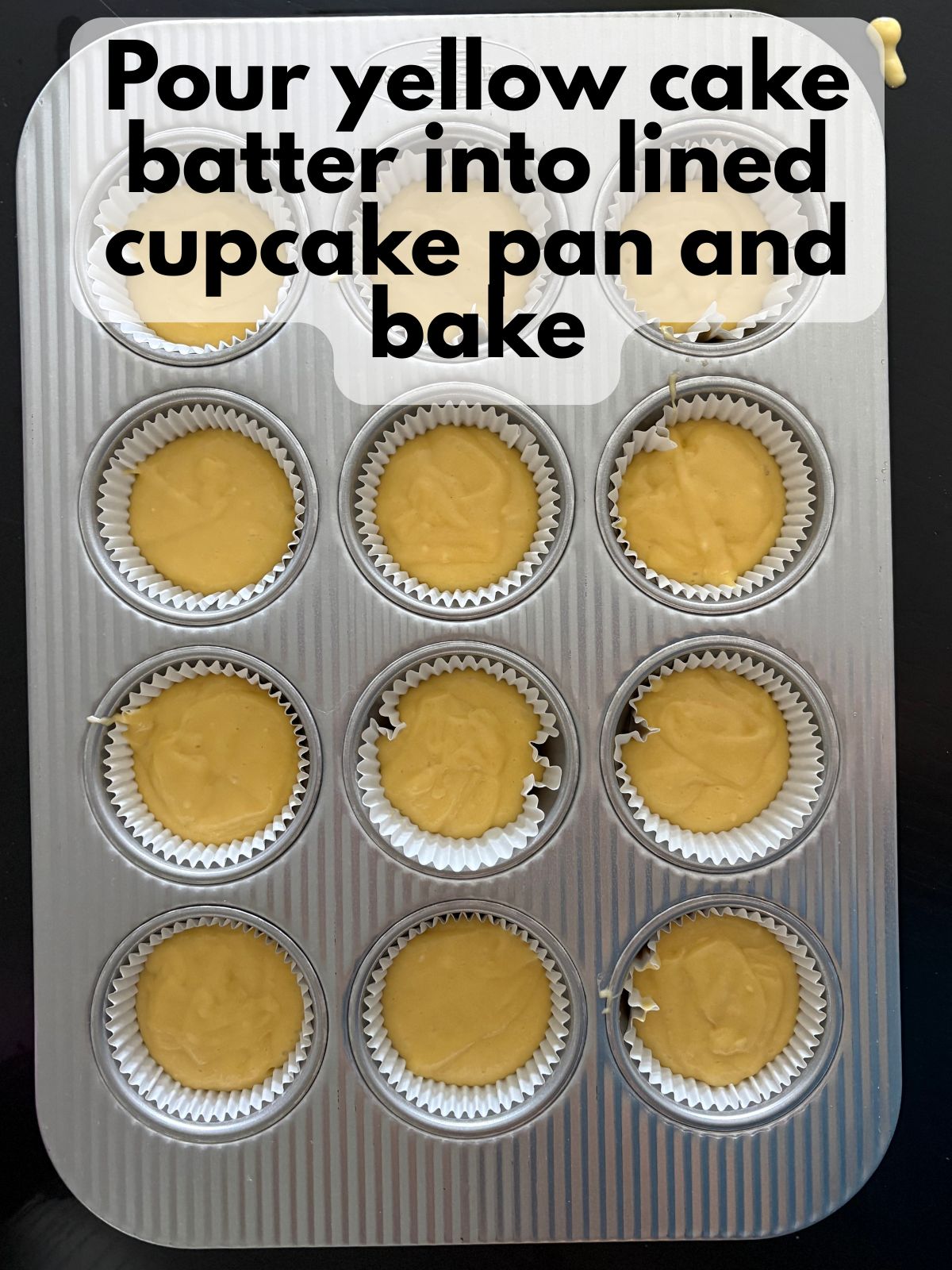 yellow cupcake batter in a lined cupcake pan
