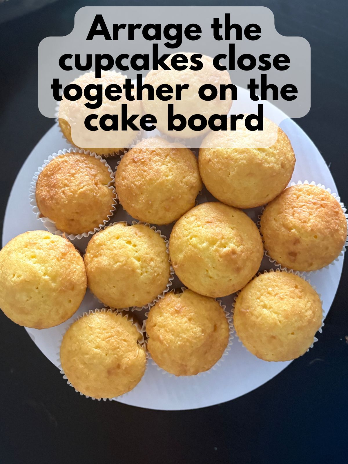 baked yellow cupcakes stuck to a cake board to form a cupcake cake