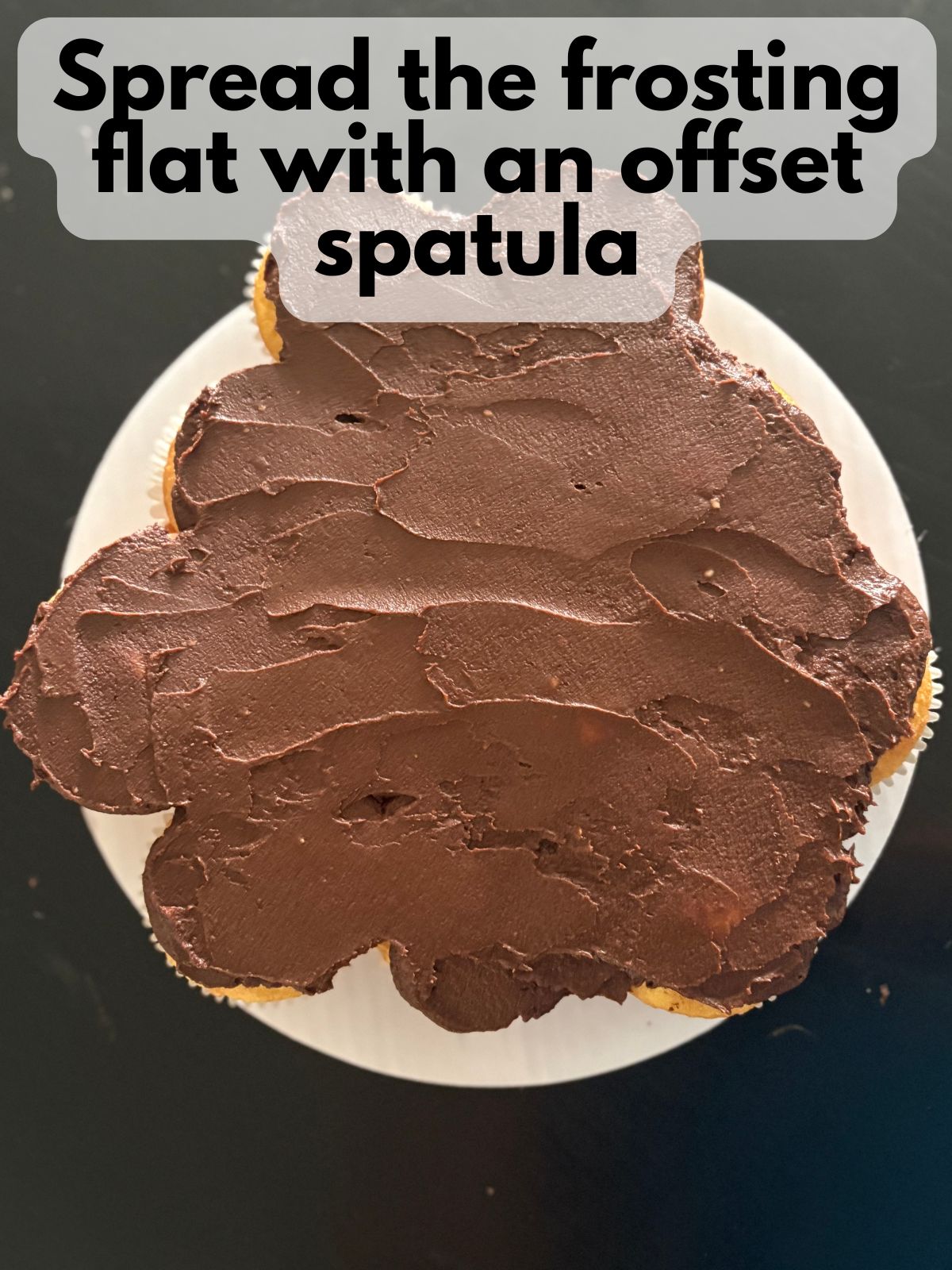 chocolate frosting spread flat on top of cupcake cake