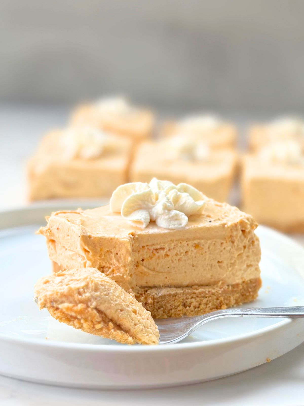 no bake pumpkin cheesecake bar on a plate with a bite taken out of it