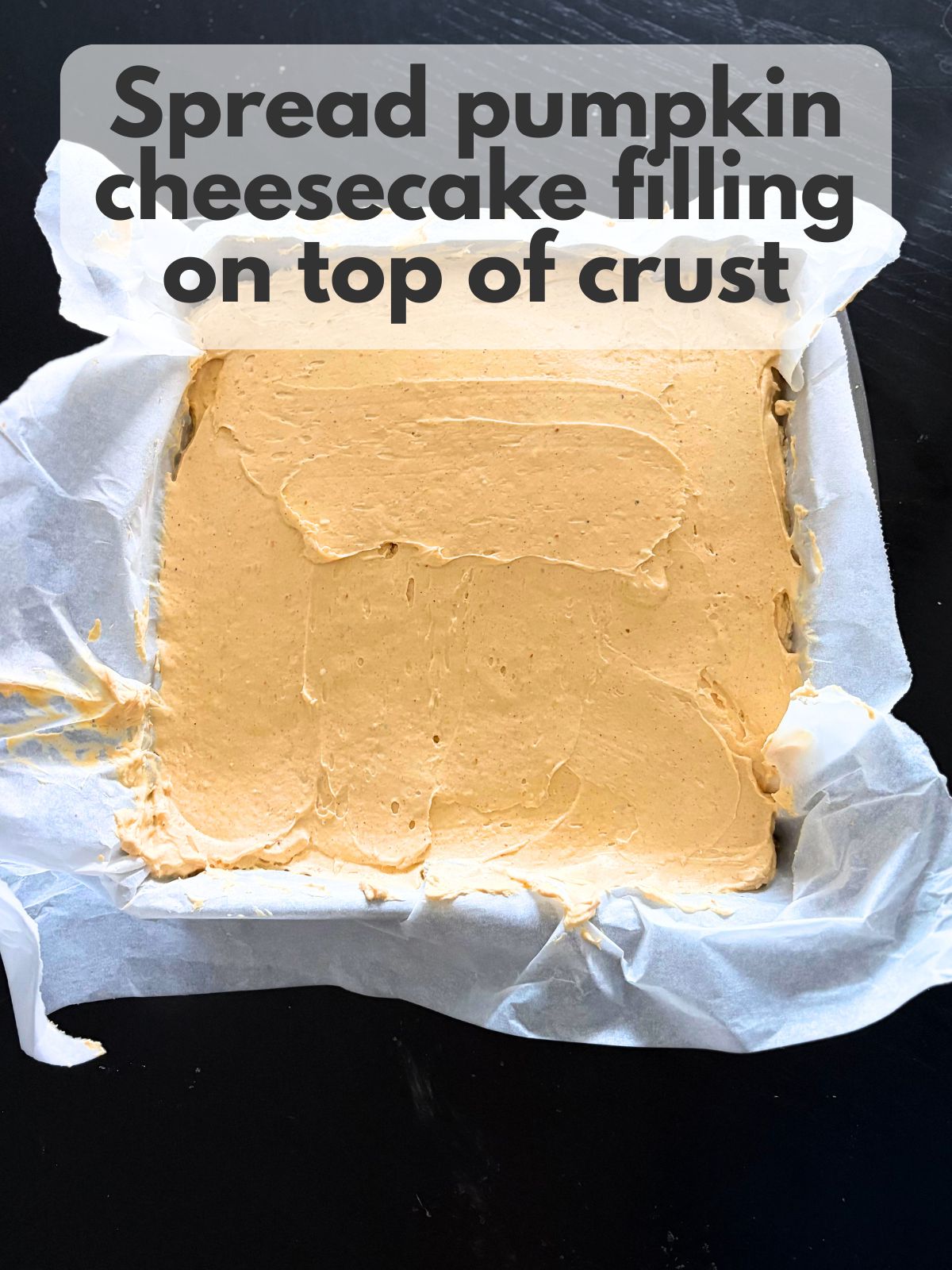 pumpkin cheesecake filling spread over graham cracker crust