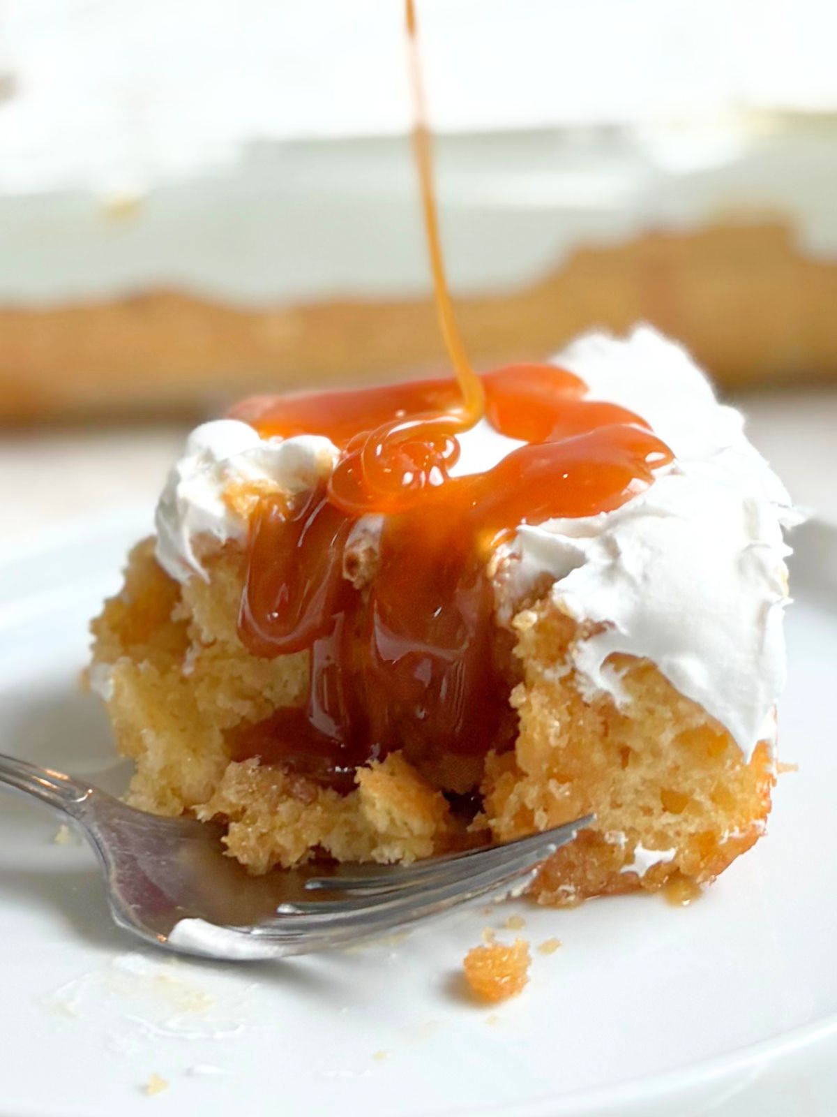 caramel being drizzled over salted caramel poke cake