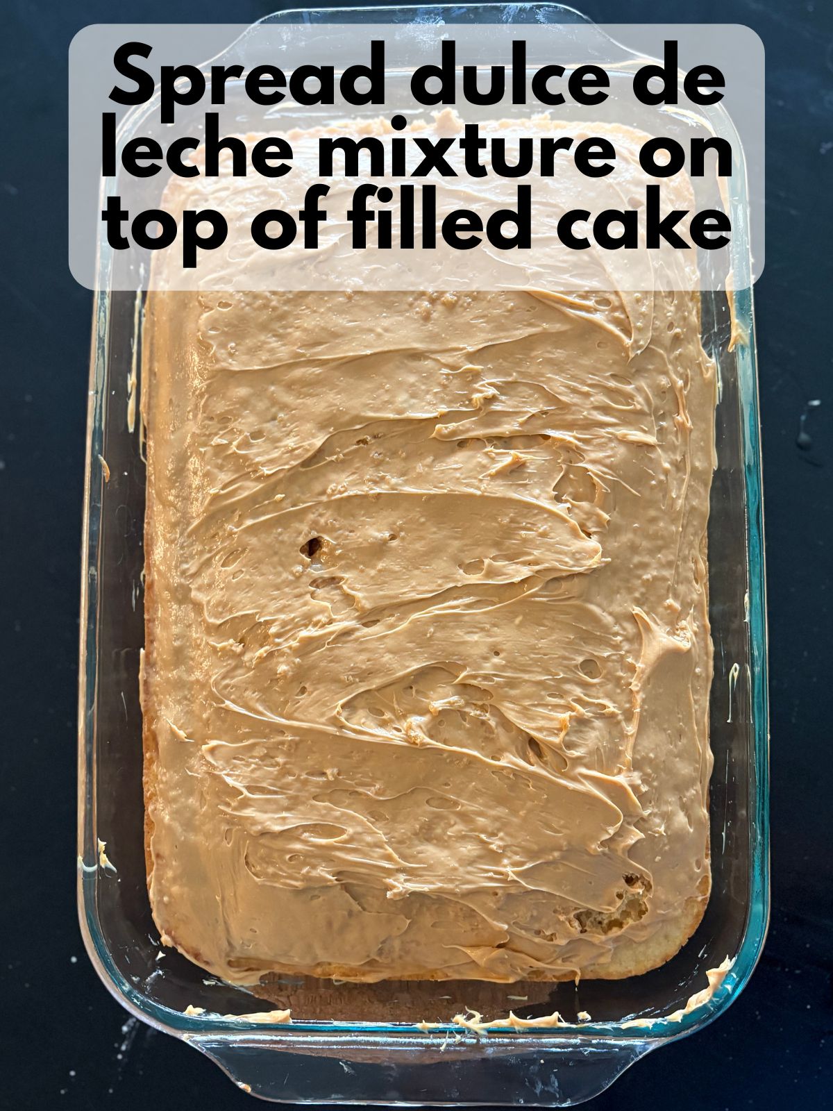 dulce de leche cream cheese frosting spread over the top of poke cake