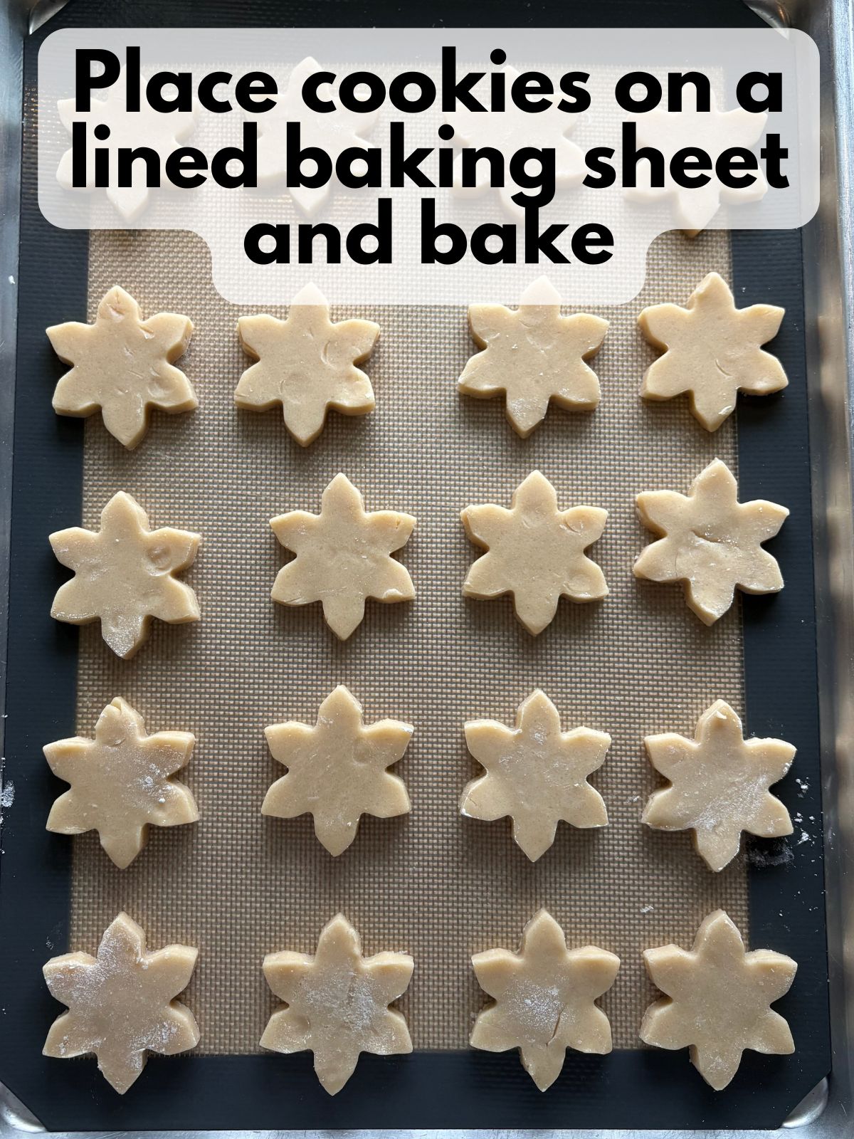 snowflake shaped cookie dough on a lined baking sheet