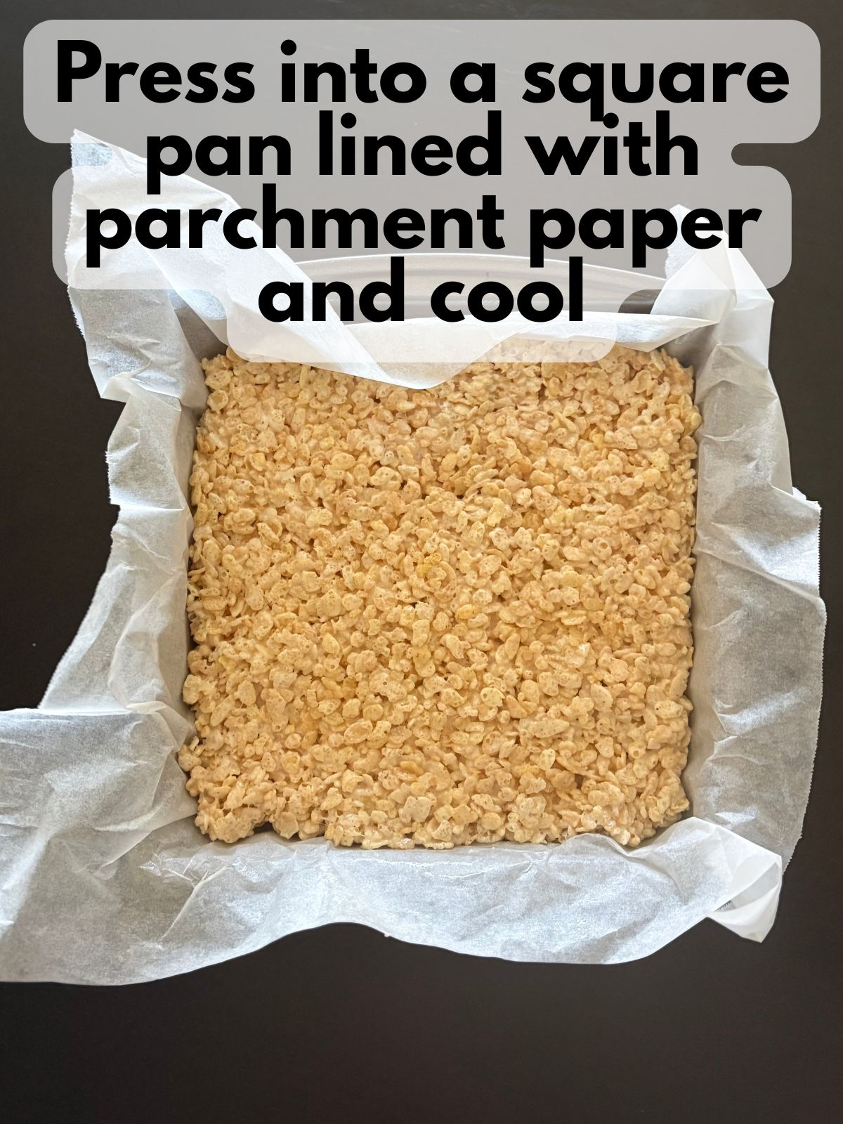 brown butter rice krispie treats pressed into a square pan lined with parchment paper