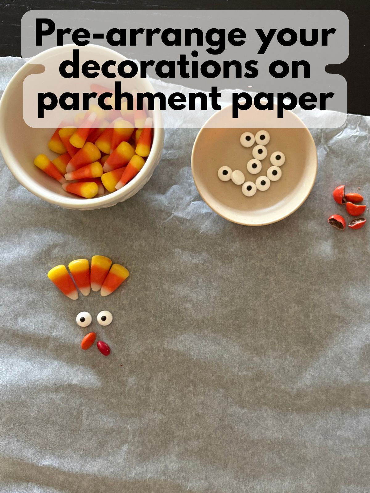 candy corn, candy eyes and M&Ms set out on a piece of parchment paper